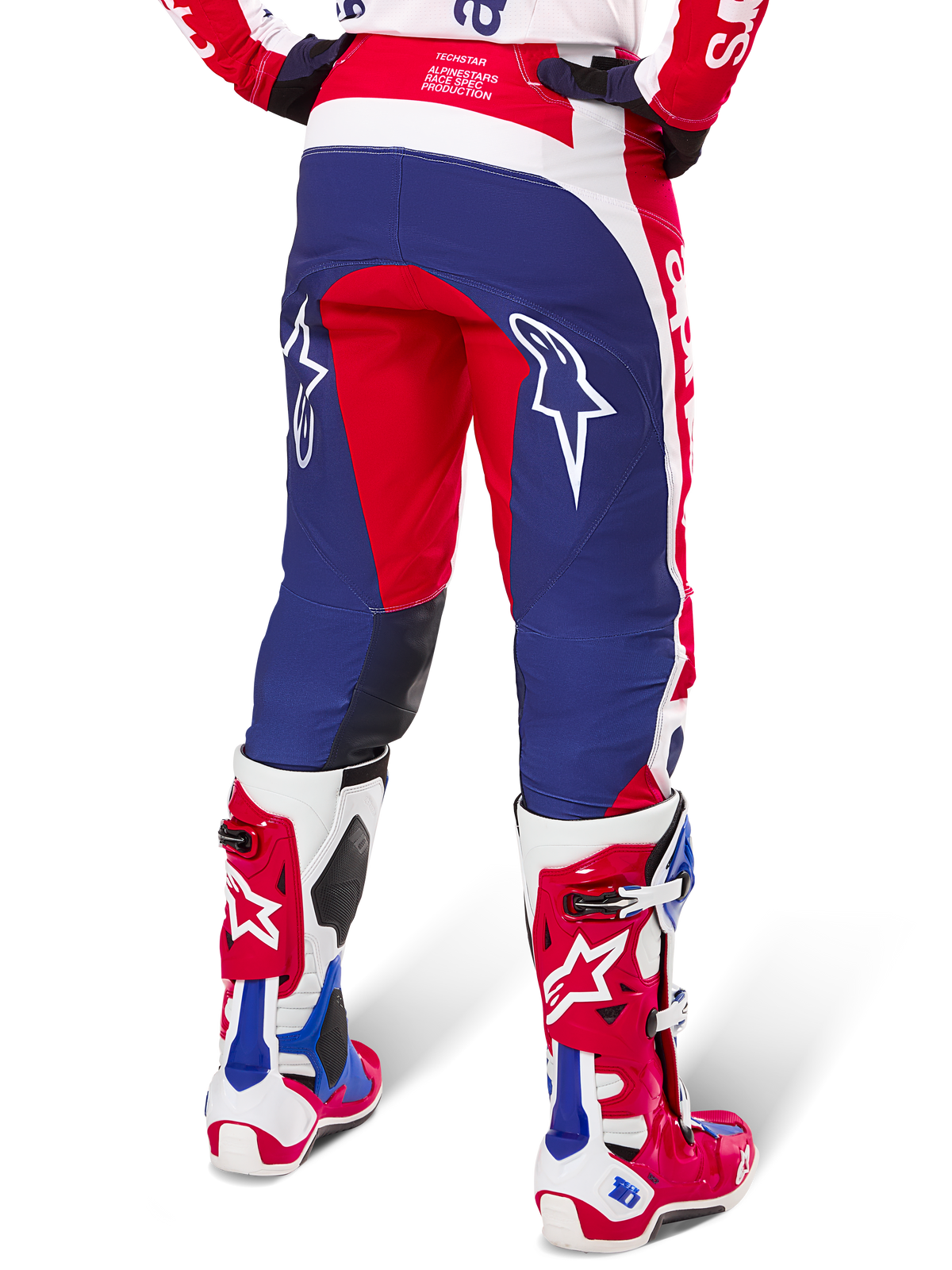 Alpinestars Limited Edition Techstar Fortitude byxor, motocrossbyxor, röda, vita och blå, vy bakifrån buren med matchande röda och vita stövlar, vita stjärnlogotyper på baksidan av låren, hållbar multipaneldesign för professionell terrängkörning