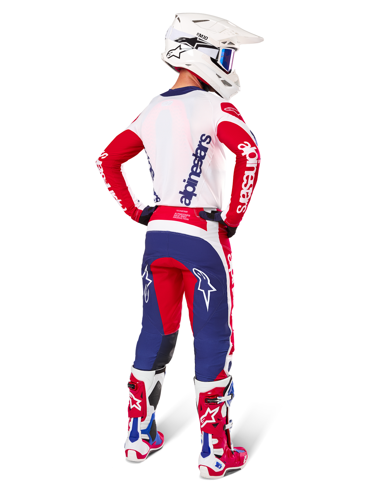 Alpinestars Limited Edition Techstar Fortitude byxor, motocrossbyxor, röd, vit och blå, visas på en förare bakifrån med matchande tröja, stövlar och hjälm, vilket framhäver den atletiska passformen och logotypernas framträdande placering.