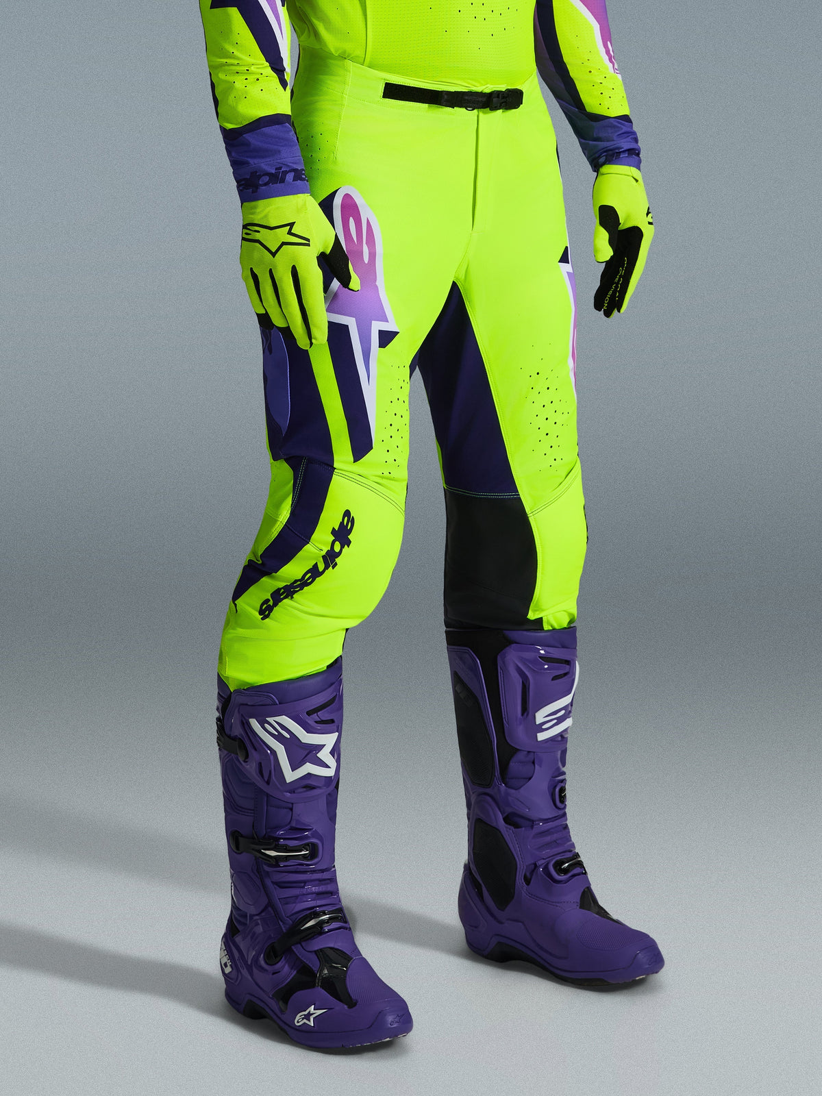 Alpinestars 2026 Supertech Vista byxor, motocrossbyxor, neongula, lila och svarta, bärs med matchande lila stövlar och gula handskar, med framträdande logotyp på låret och en atletisk passform.