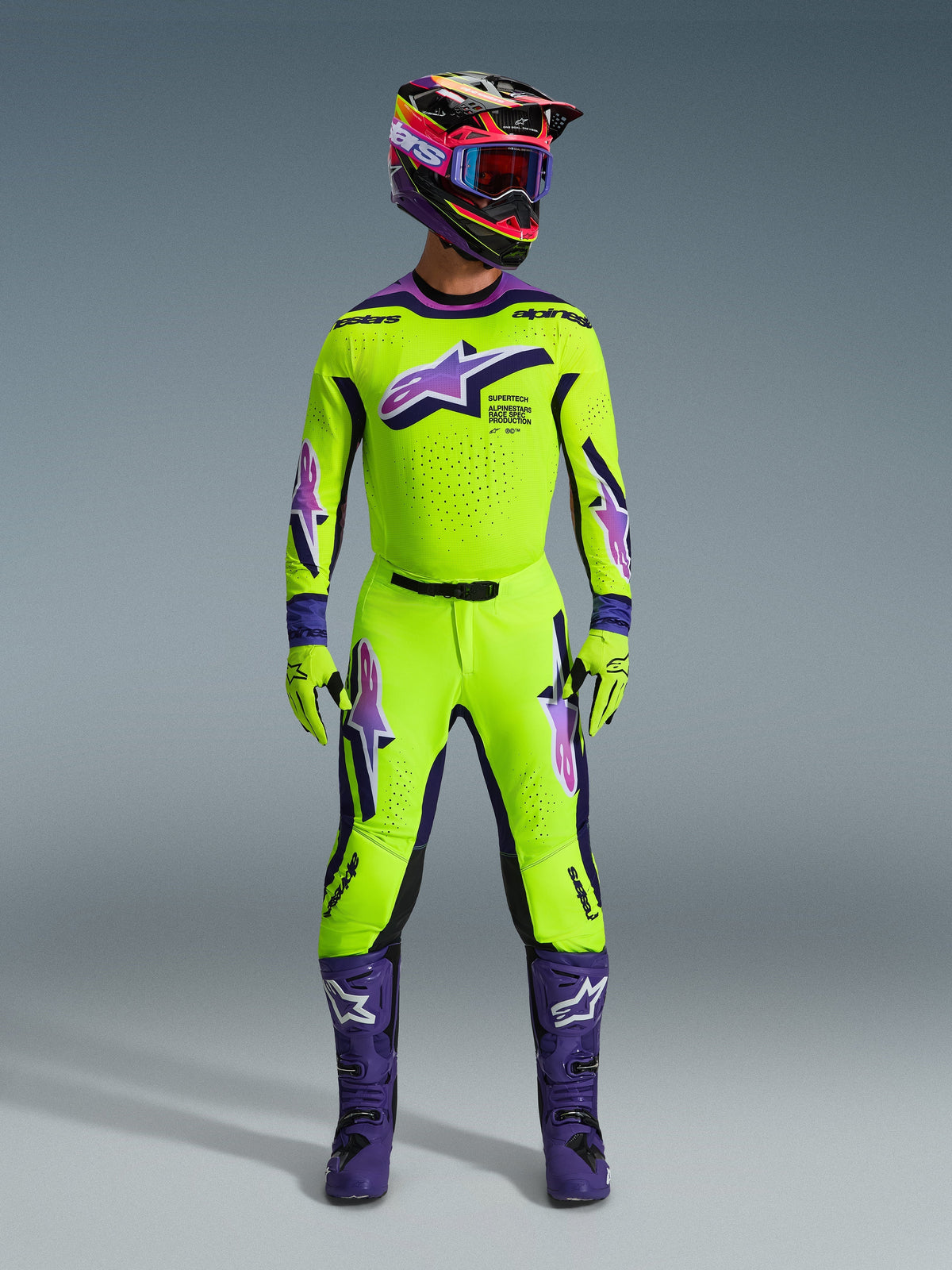 Alpinestars 2026 Supertech Vista byxor, motocrossbyxor, neongula med lila och svarta detaljer, bärs som en del av ett koordinerat racingställ med matchande tröja, hjälm och lila stövlar, med en professionell atletisk passform och framträdande logotyper för offroad-prestanda.