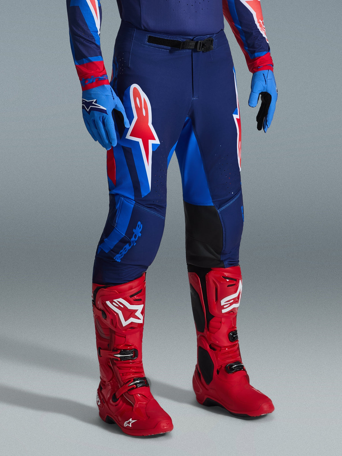 Alpinestars 2026 Supertech Vista Gear Set, Motocross pants and boots, navy blue with red and light blue panels, large A-star logo on the thigh, bright red racing boots, blue gloves, professional athletic race fit for motocross racing