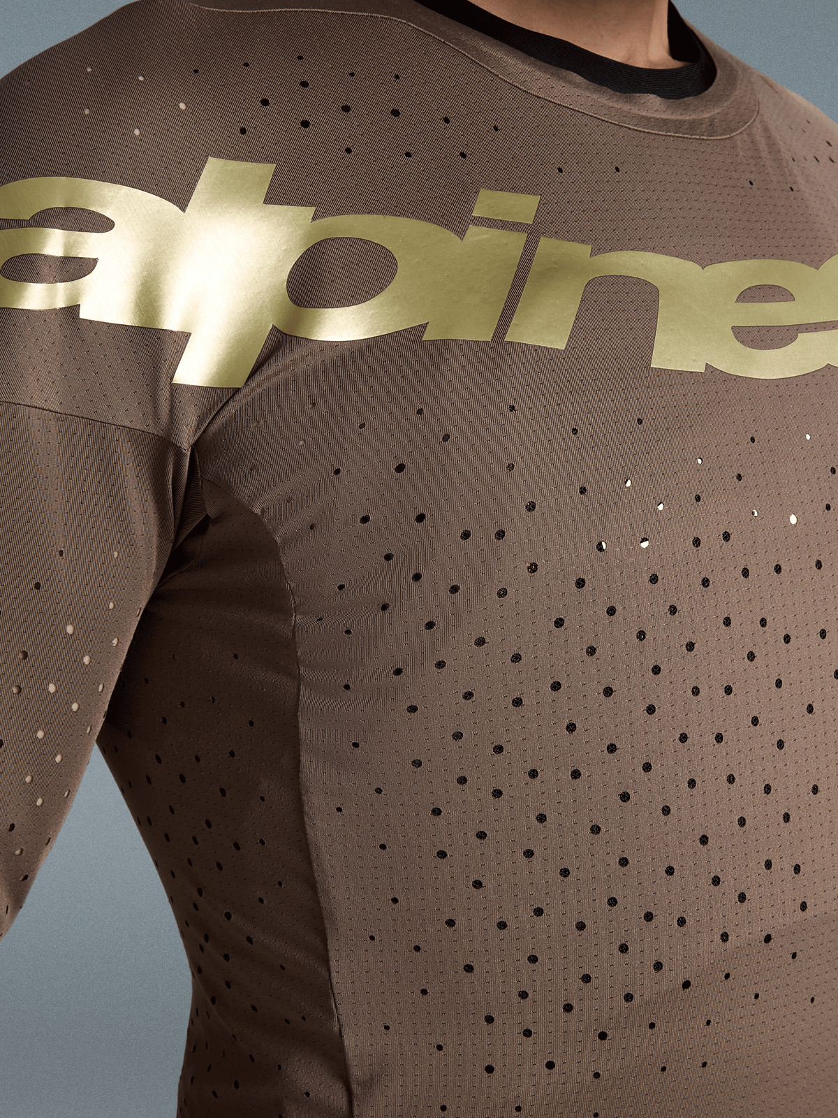 Alpinestars Begränsad Upplaga Supertech Air Gold tröja, motocrossracingtröja, brun och guld, närbild med laserutskuren ventilation och stretchnät.