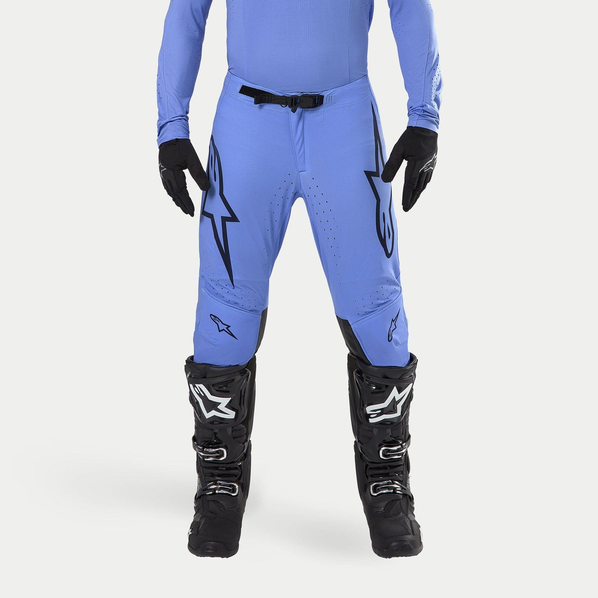 Alpinestars 2024 Supertech Dade byxor, motocrossbyxor, ljusblå med stora svarta Astars-logotyper på låren, svart midjespänne, bärs med svarta motocross-stövlar och matchande blå topp, professionell utrustning för terrängkörning