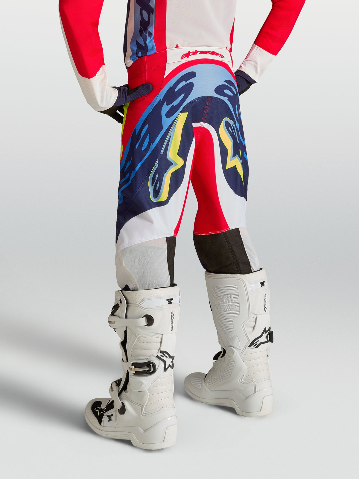 Alpinestars 2027 Supertech Dyna ungdomsbyxor, röda och marinblå motocrossbyxor, sedda bakifrån på en ung förare.