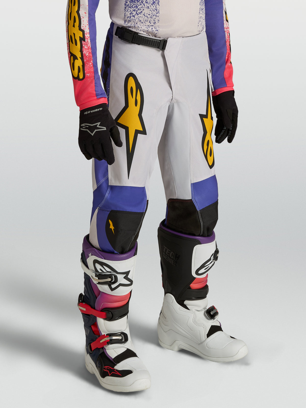 Alpinestars 2027 ungdom Fluid Drag byxor, blå och lila motocrossbyxor för barn med guldgrafik och ergonomisk förböjd design.