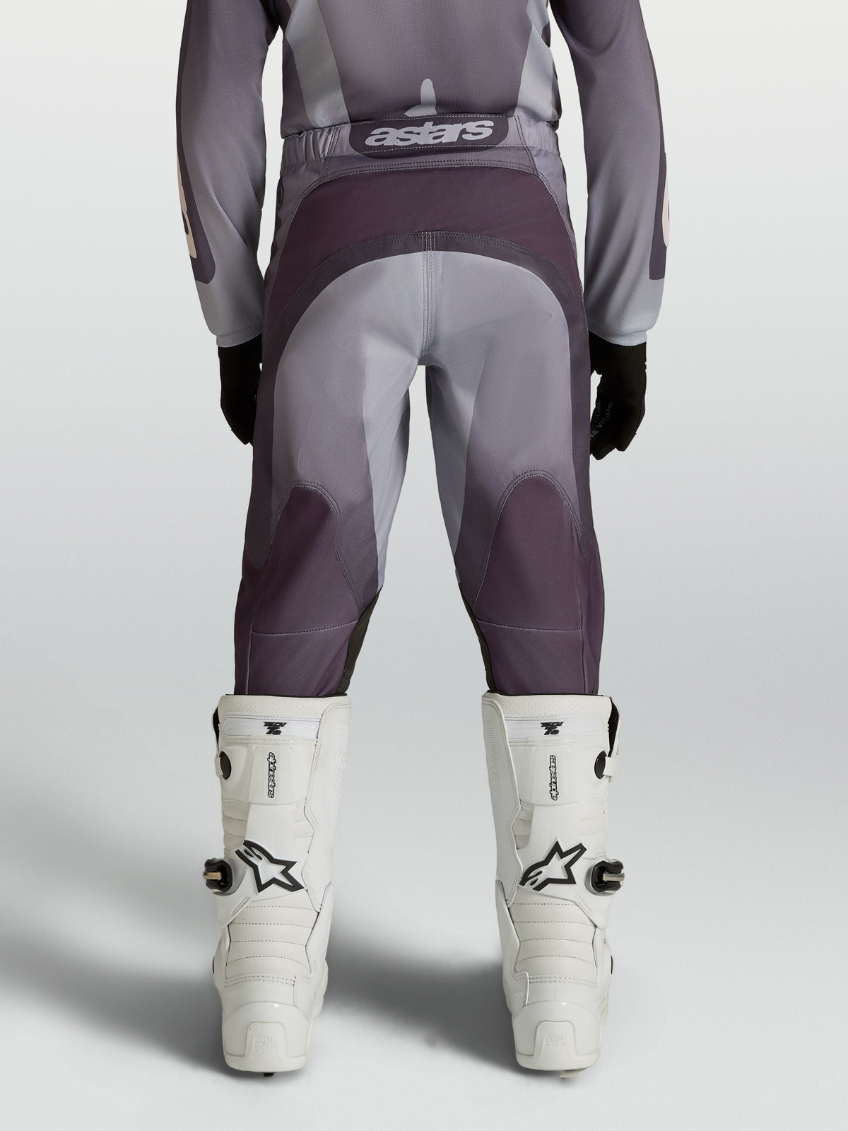 Alpinestars 2027 Fluid Amber motocrossbyxor för ungdom, grå och sand, förstärkt säte och stretchpaneler, bakifrån på modell.