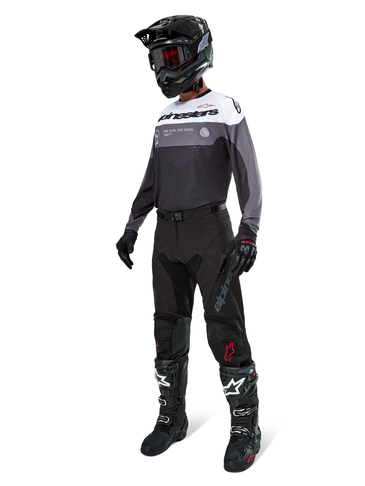 Alpinestars Pro-Dura-tröja i Black Magnet White, bärs av en motocrossförare i komplett utrustning inklusive svarta byxor, svart hjälm med goggles och svartvita stövlar. Tröjan har en teknisk färgblocksdesign med vita, grå och svarta paneler, konstruerad för enduro- och offroad-prestanda.