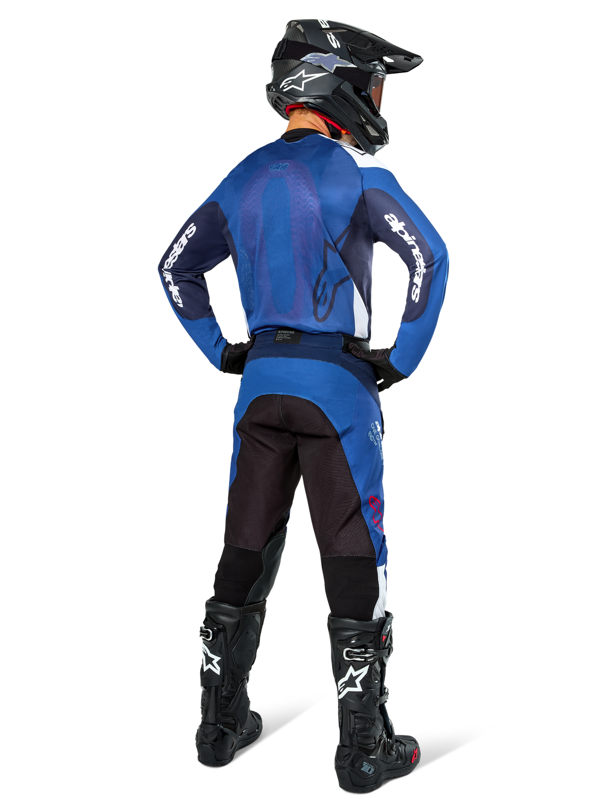 Motocross rider from the back wearing Alpinestars Pro-Dura Jersey in Navy and Bright Blue, matching blue and black pants, black motocross helmet with goggles, and black boots, showing a coordinated off-road racing outfit