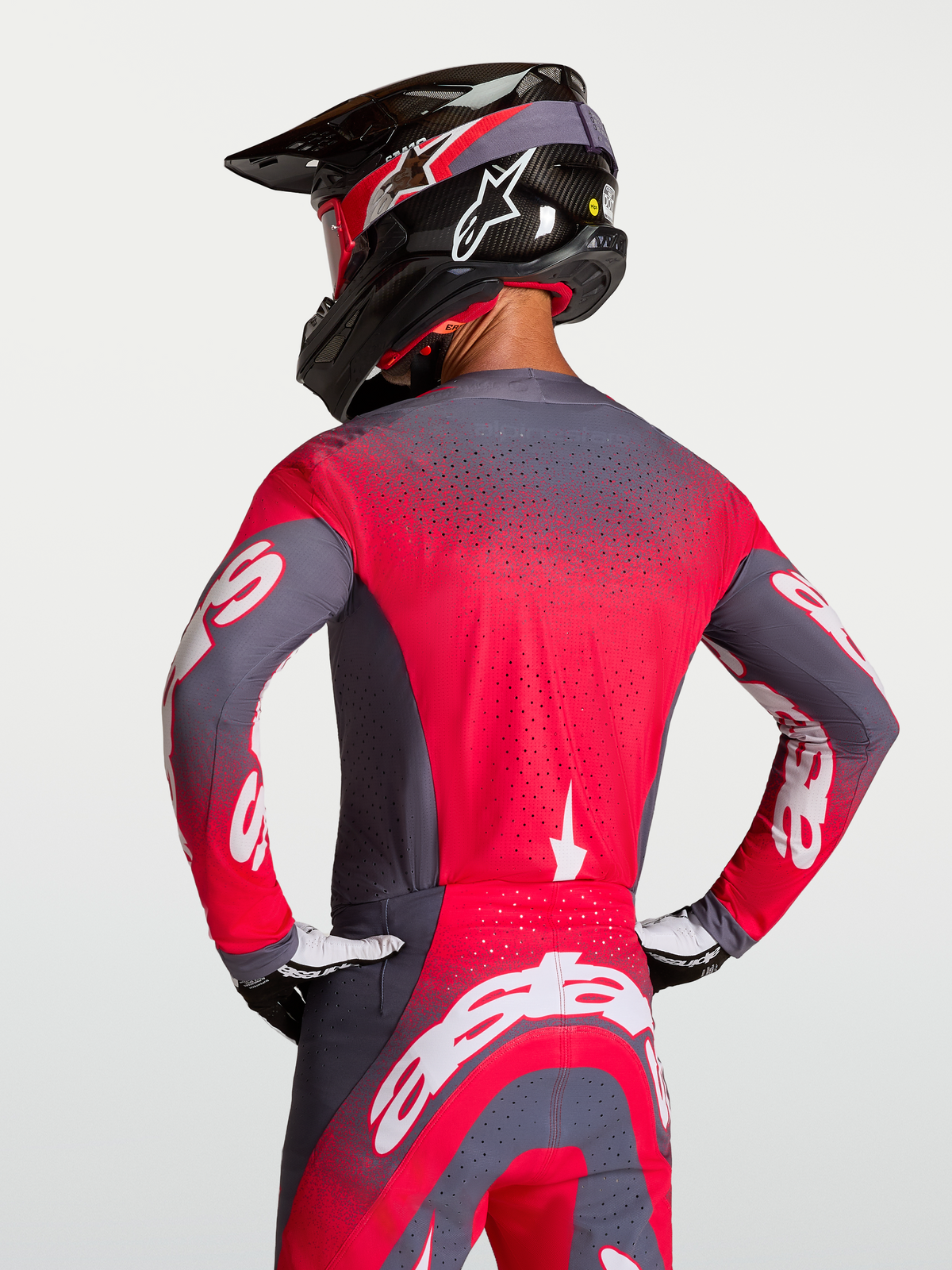 Alpinestars Supertech Hiten AFD tröja, motocrosströja i grå och röd, sedd bakifrån på en förare med ventilation och pro racing-passform.