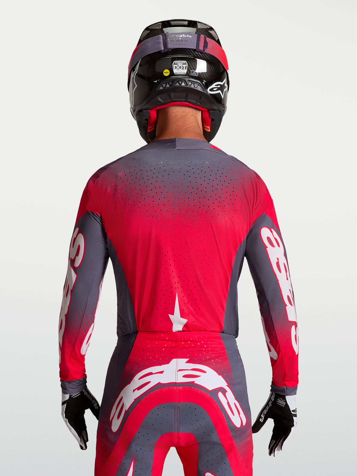 Alpinestars Supertech Hiten AFD tröja, motocross-tröja för herr, grå och röd fluo, ventilerad mesh-konstruktion med laserutskurna perforeringar, vit logotypgrafik, bärs bakifrån med matchande racingutrustning.