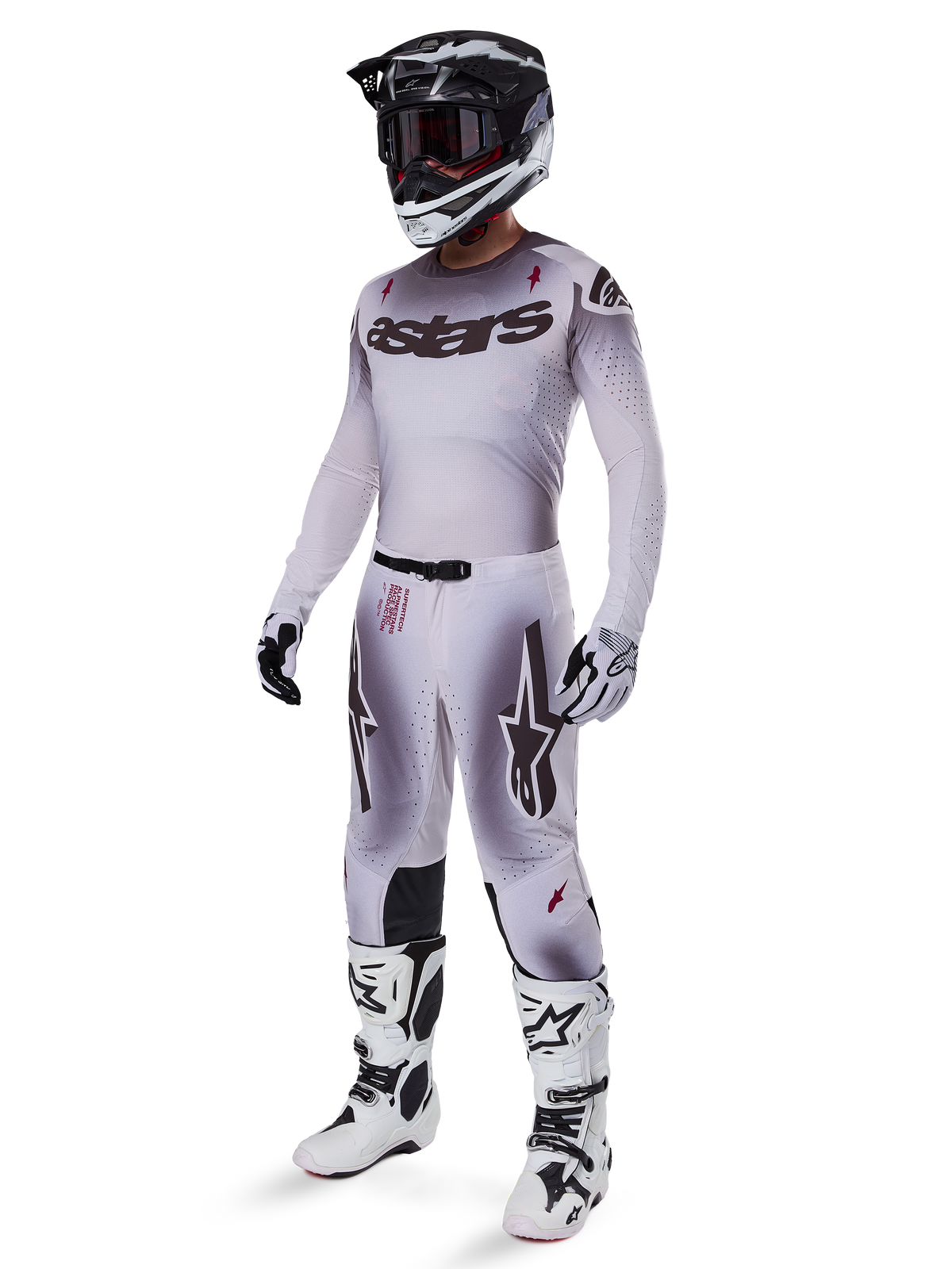 Motocrossförare som bär 2025 Supertech Maker-byxor i Silver Black, koordinerad med en matchande silver- och gråfärgad tröja, svart och vit hjälm samt vita racingstövlar, teknisk atletisk passform för professionell terrängprestanda.