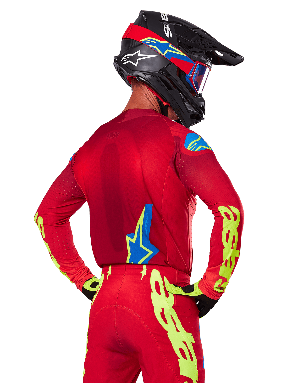 Bakifrån vy av en motocrossförare som bär Alpinestars 2025 Supertech Maker-utrustningsset i rött, med en röd tröja med neongul branding på ärmarna, matchande röda byxor, en svart hjälm med blå och röda detaljer samt koordinerade svarta och gula handskar.