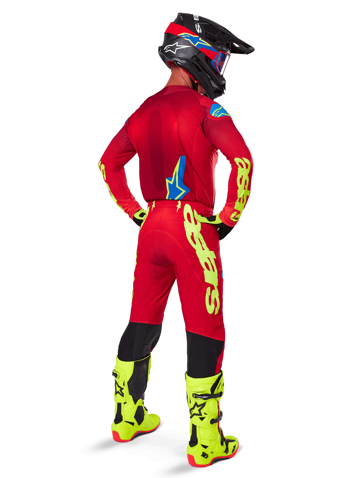 Motocrossförare sedd bakifrån iförd Alpinestars 2025 Supertech Maker-utrustningsset, klaröd tröja med neongul logotyp, matchande röda byxor med gula detaljer, svart hjälm med röda och blå detaljer, neongula stövlar, professionell racingutrustning för terrängkörning