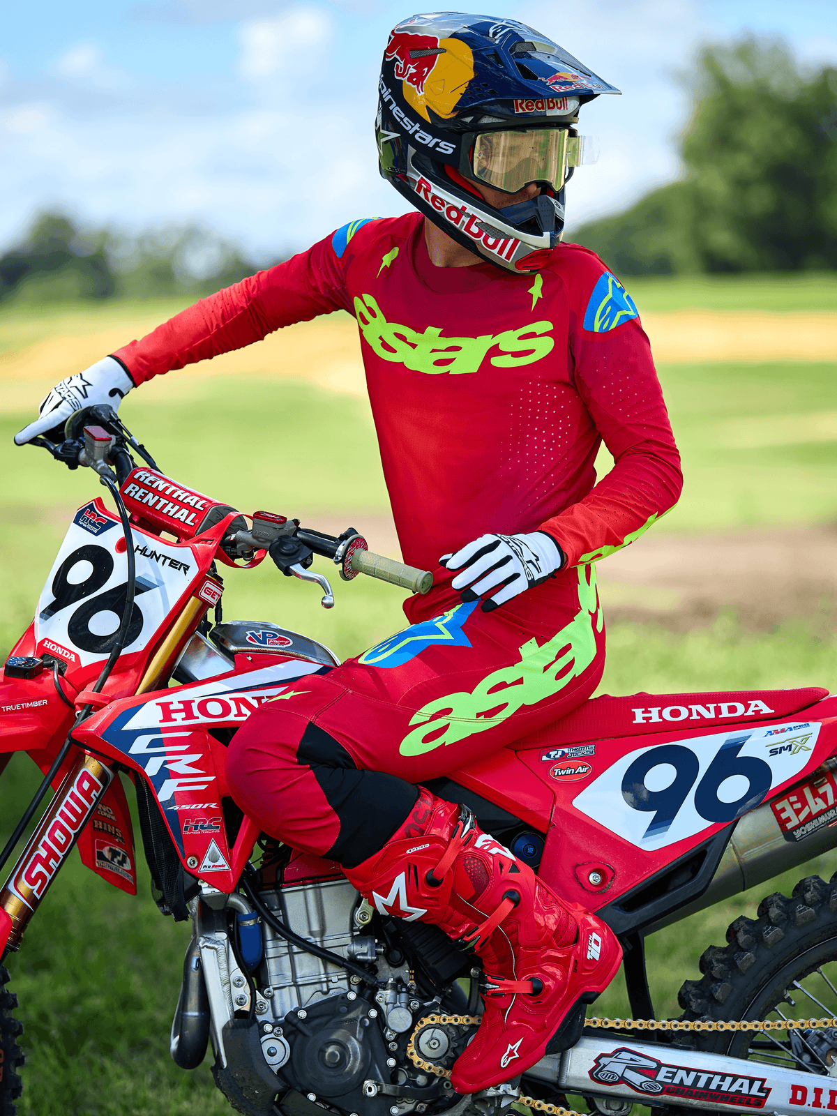 Motocrossförare i Alpinestars 2025 Supertech Maker Jersey, klarröd med neongul ”astars”-logotyp, matchande röda byxor och stövlar, vita och svarta handskar, sittande på en röd Honda racingcykel i utomhusmiljö.