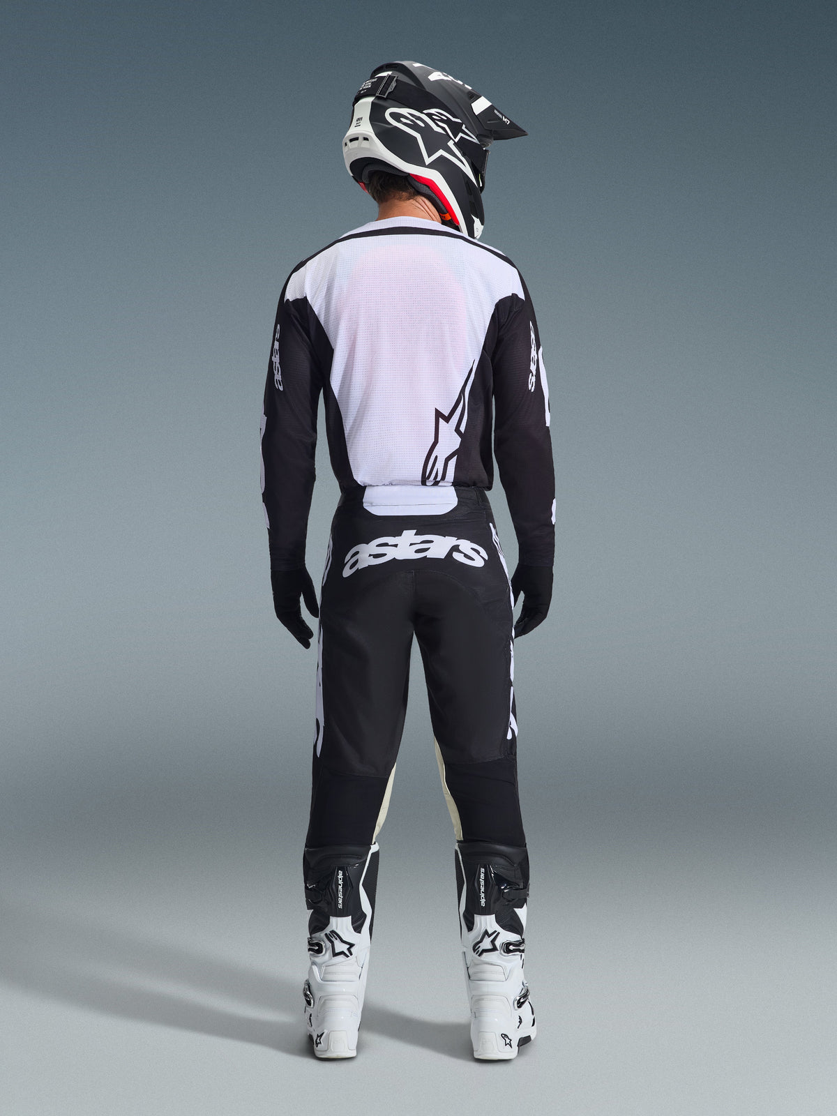 Alpinestars 2026 Racer Air Riway Gear Set, Motocross Gear, Black and White, rear view of rider wearing ventilated jersey with white mesh panels, matching pants with bold astars branding on the seat, coordinated with white and black motocross boots and helmet
