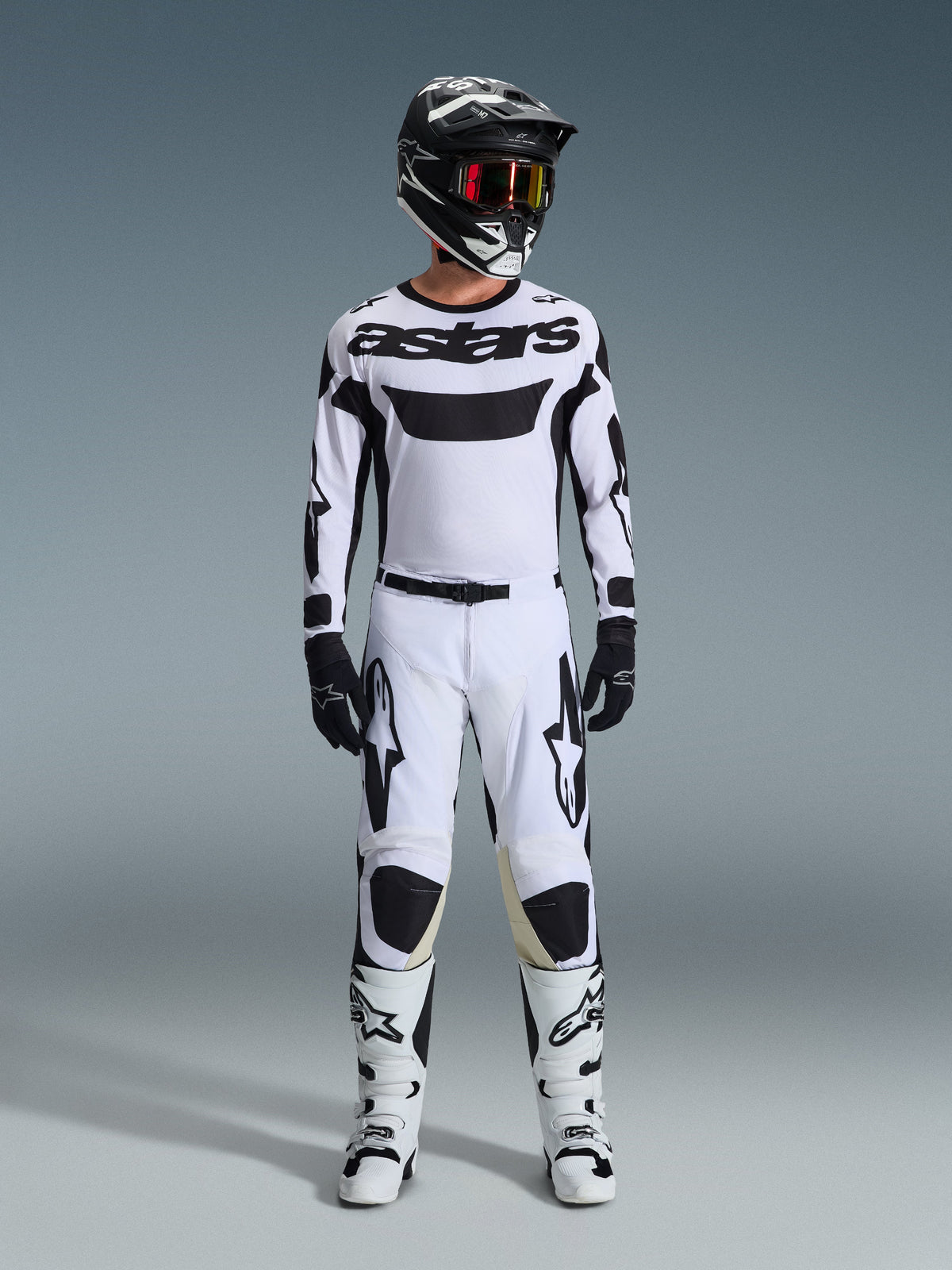 Alpinestars 2026 Racer Riway-tröja, motocrosströja, vit och svart, bärs som ett komplett raceställ med matchande byxor, svart hjälm med röda goggles, svarta handskar och vita stövlar, med framträdande svart 'astars'-branding och stjärnlogotyper.