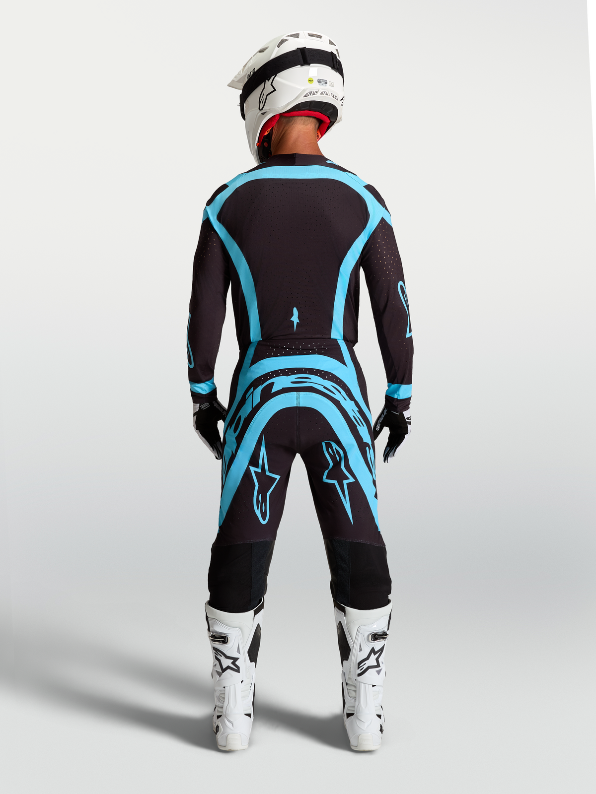 Alpinestars Supertech Vesta utrustningsset, svart och turkos motocrossutrustning för terrängkörning, vy bakifrån med atletisk passform på modell.