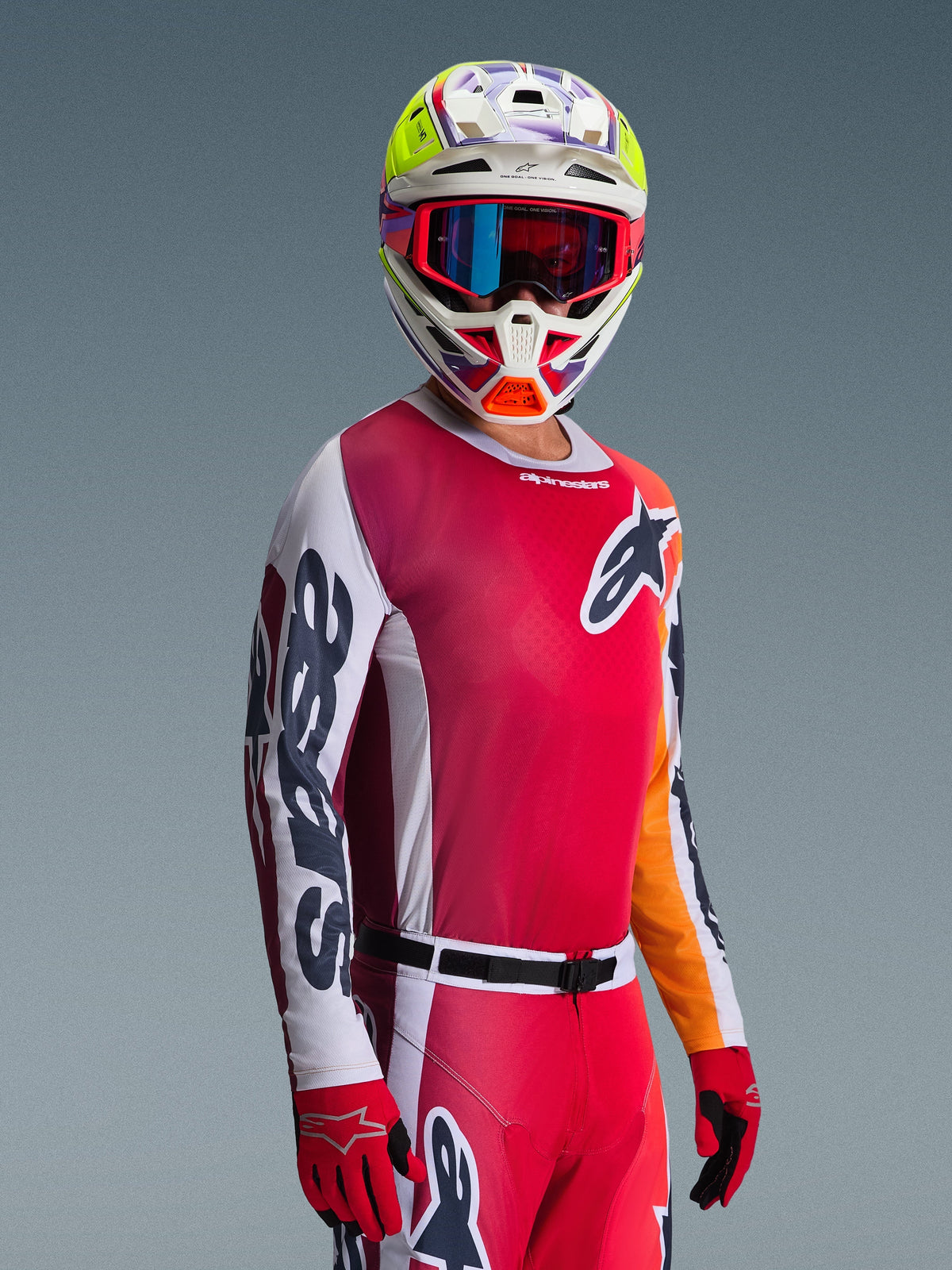 Motocrossförare klädd i 2026 Racer Portl Jersey, röd med vita och mörkgrå ärmar, tillsammans med matchande motocrossbyxor, flerfärgad hjälm med blå goggles och röda handskar, studiobild