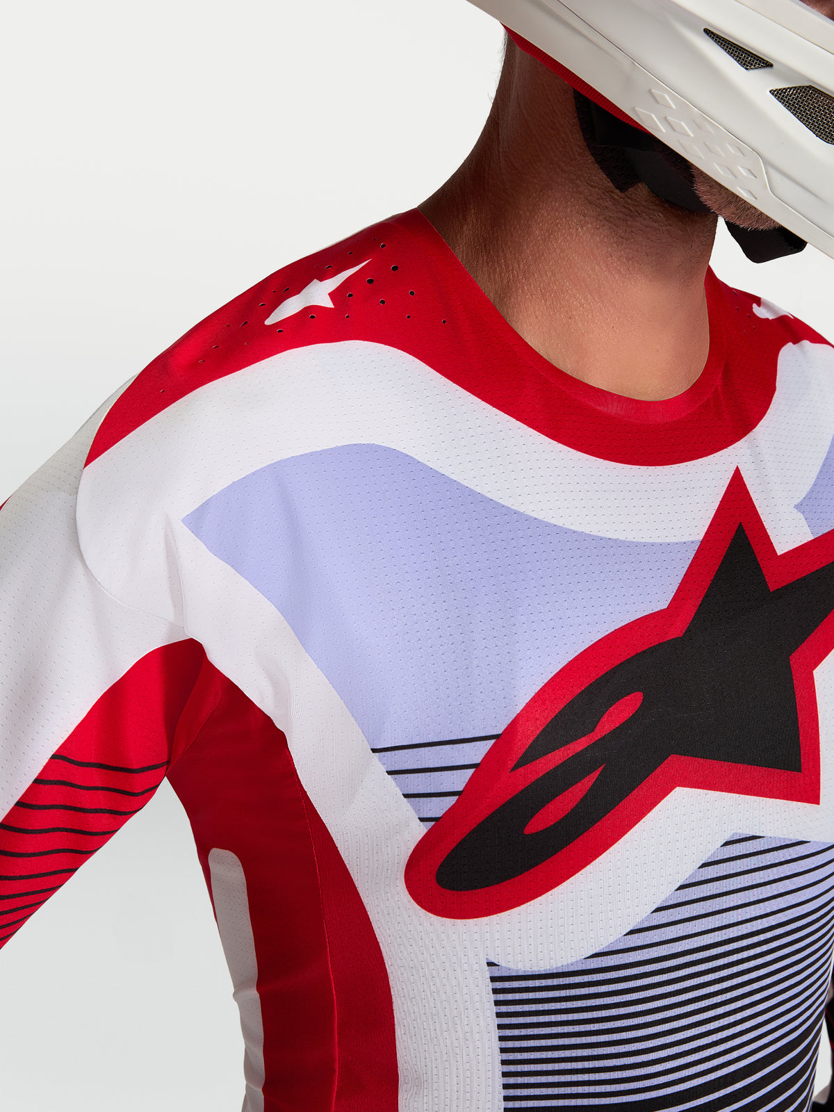 Alpinestars Techstar Maven tröja, motocrosströja i rött, vitt och lavendel, närbild på bröst och axel med laserskurna ventilationshål och framträdande logotyp, atletisk racingpassform.