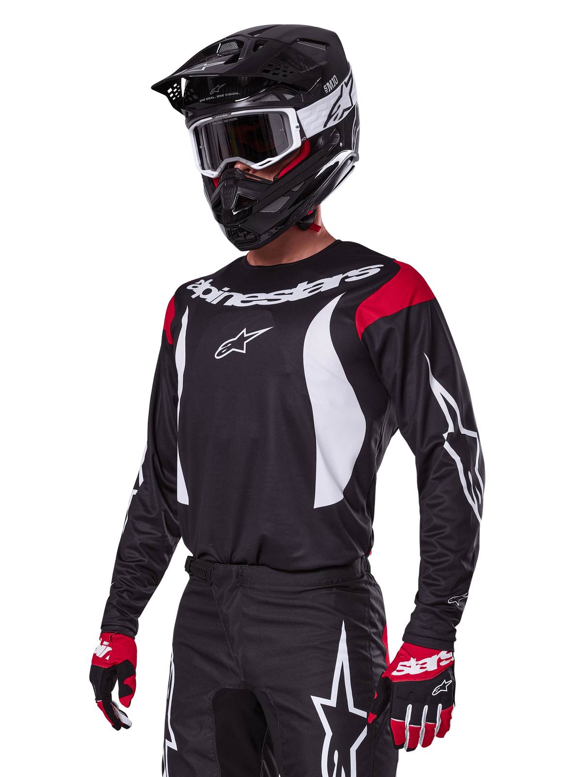 Motocrossförare i Alpinestars 2025 Fluid Haul utrustningsset, svart tröja med röda axelpaneler och vit grafik, matchande svarta byxor med vita stjärnlogotyper, röda och svarta handskar, svart hjälm med vita detaljer och goggles, koordinerad motocrossutrustning