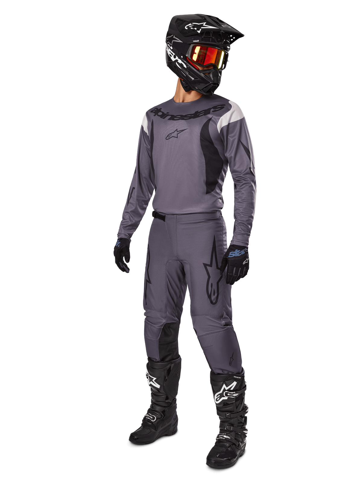 Motocrossförare iklädd Alpinestars 2025 Fluid Haul-utrustningsset i grått, inklusive grå tröja och byxor med svarta detaljer, svart hjälm med rödaktiga goggles, svarta handskar och svarta stövlar med vita logotyper, komplett utrustning för offroad-racing