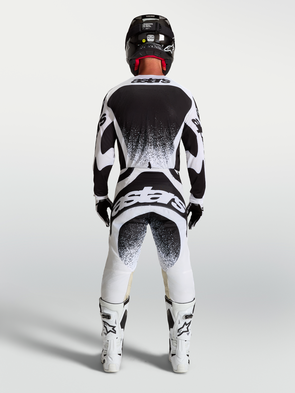 Alpinestars Techstar Swan tröja och gear set, svart och vit motocross-outfit för herr med splattergrafik sedd bakifrån.