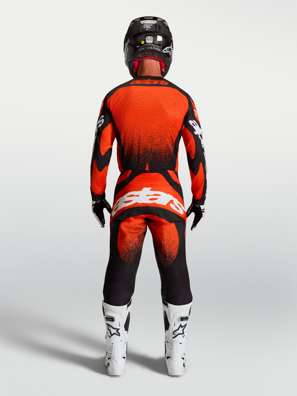 Alpinestars Techstar Swan tröja och gear set, motocrossutrustning för herrar i rött och svart med atletisk tävlingspassform, vy bakifrån med vit Astars-logotyp, vita stövlar och hjälm.