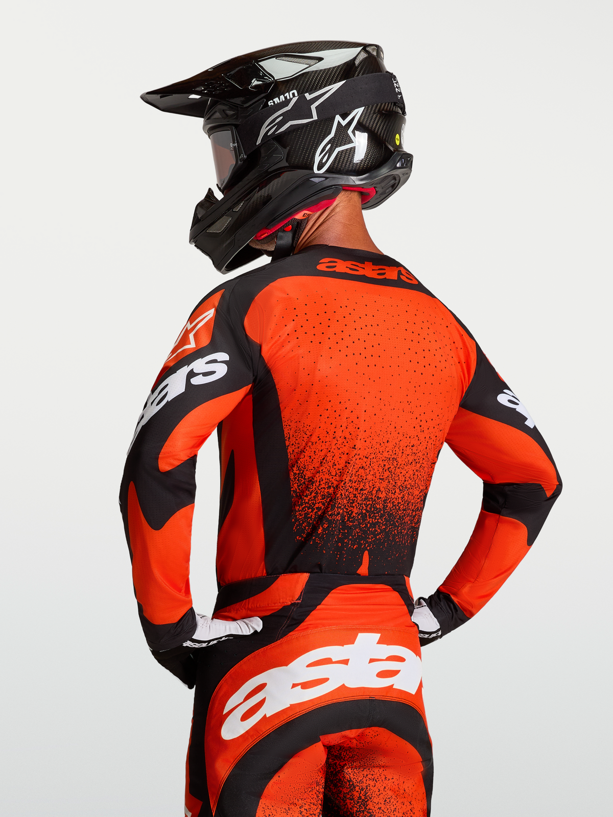 Alpinestars Techstar Swan tröja, motocrosströja i rött och svart med atletisk race fit, laserskuren ventilation på ryggen, bärs av modell med hjälm bakifrån.