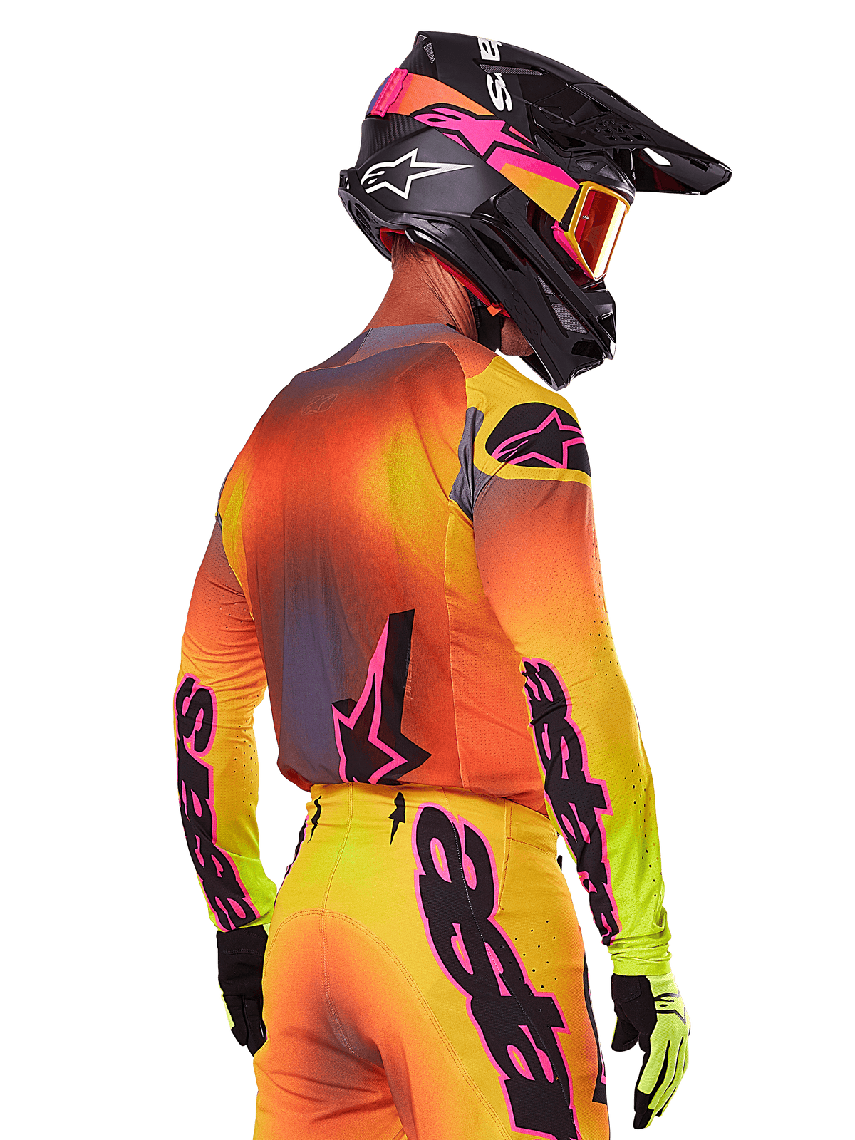 Motocrossförare sedd snett bakifrån iklädd Alpinestars 2025 Supertech Lipan Gear Set, med en färgtoning i gult, orange och rött med svarta och rosa logotyper, svart hjälm med rosa detaljer och orangea goggles, professionell utrustning för terrängkörning.