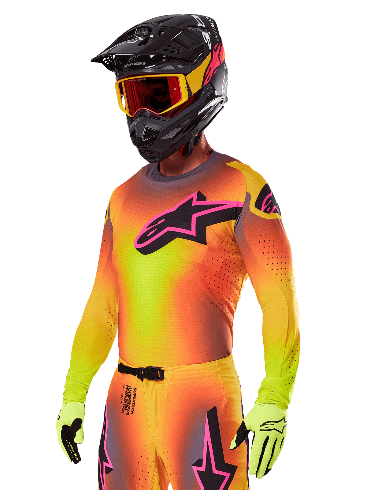 Motocrossförare i Alpinestars 2025 Supertech Lipan utrustningsset, gul och orange tröja med färgövergång, rosa och svart Astars-logotyp, neongula handskar, svart hjälm med röda goggles, professionell utrustning för terrängkörning