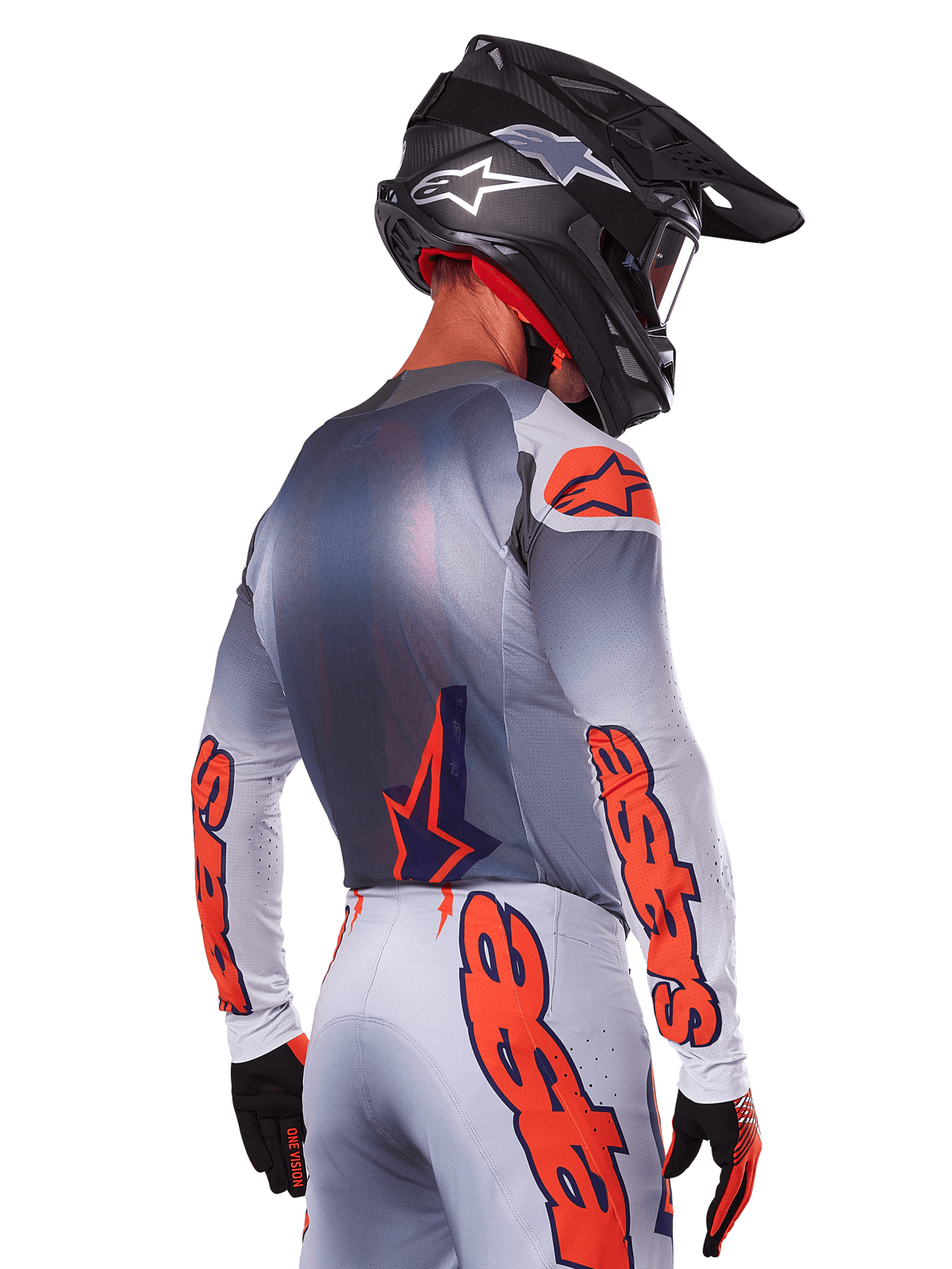 Motocrossförare sedd bakifrån i Alpinestars 2025 Supertech Lipan Jersey i Gray Orange Fluo, med framträdande orange logotyper på ärmar och rygg, matchande byxor och svart hjälm, professionell racingutrustning för terrängkörning