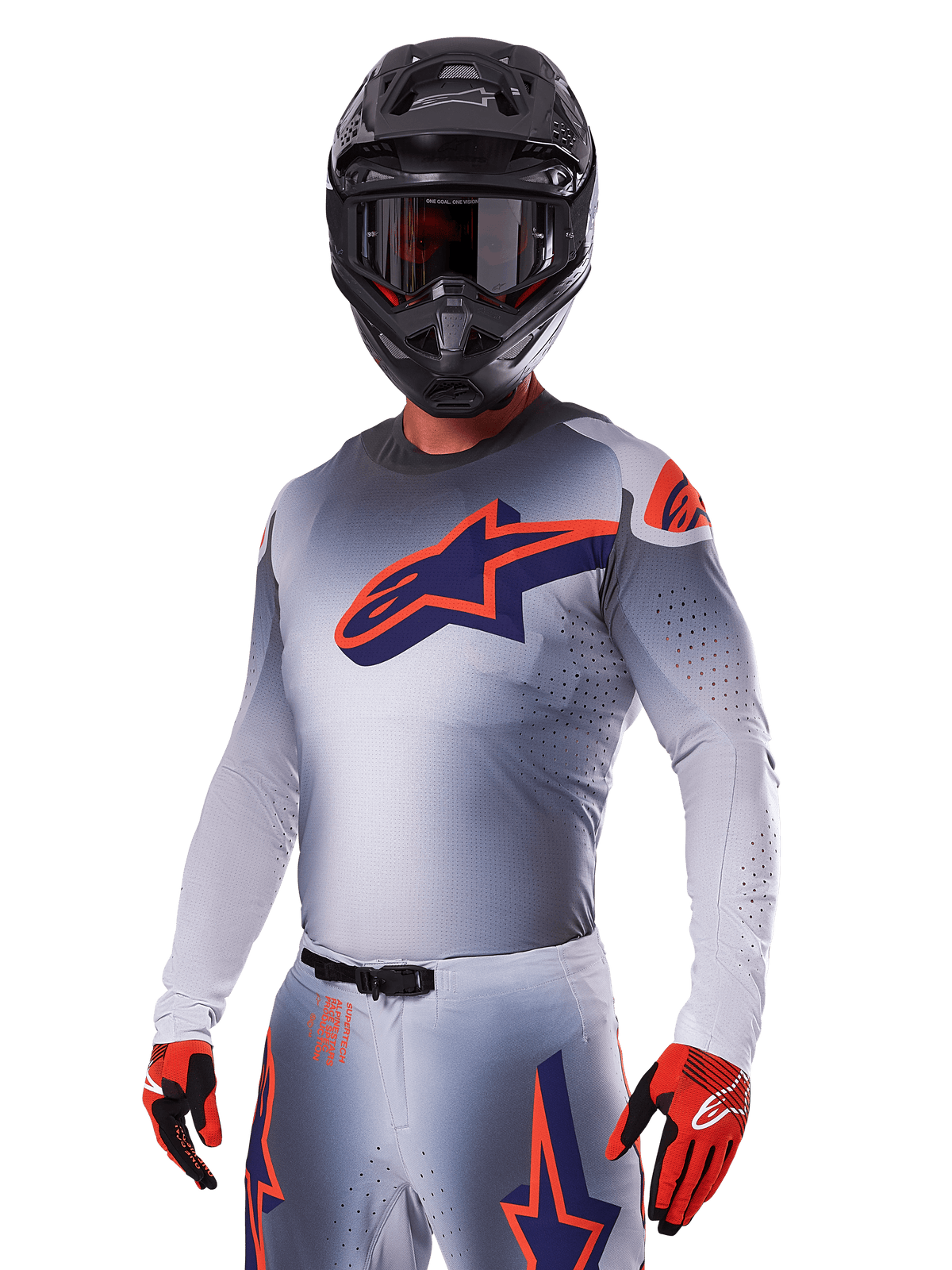 Motocrossförare i Alpinestars 2025 Supertech Lipan-utrustningsset, grå tröja och byxor med marinblå och orange detaljer, mattsvart hjälm med goggles och röda och svarta handskar, atletisk funktionsutrustning för terrängkörning