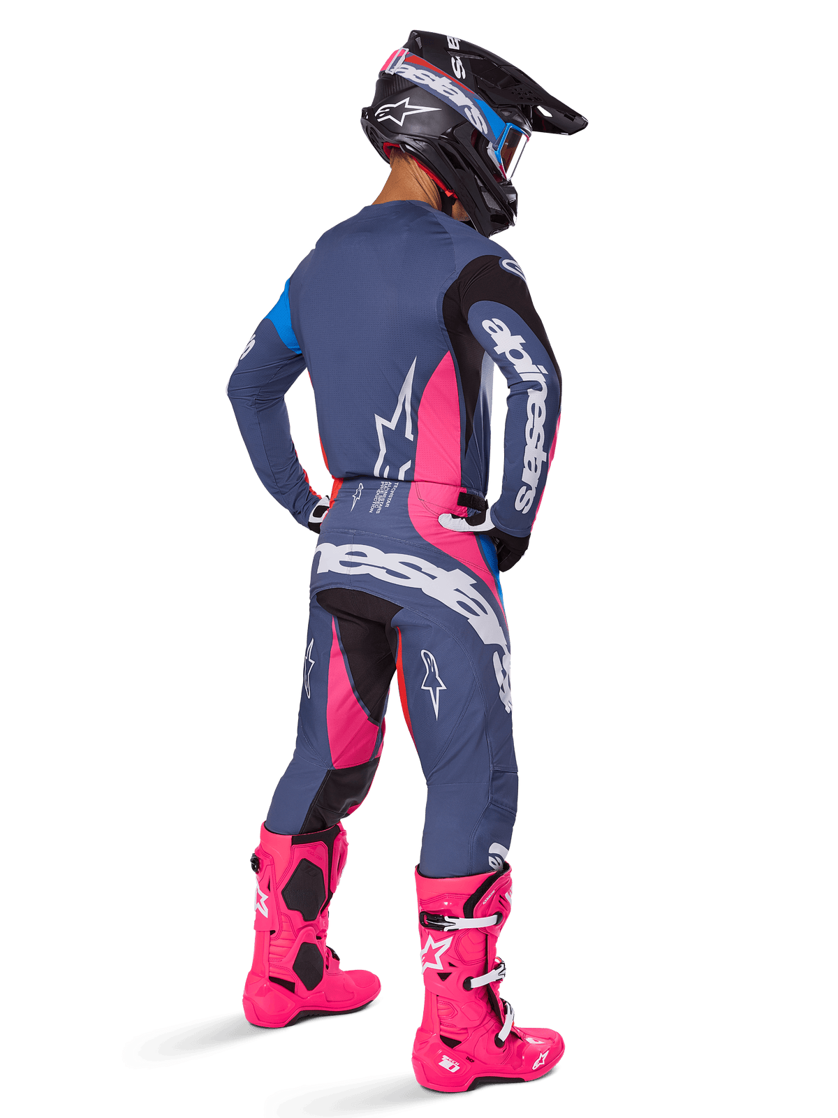 Motocrossförare sedd bakifrån, bär Alpinestars 2025 Techstar Dreem-utrustningsset, grått med livfulla rosa och vita detaljer, svart och vit hjälm och klarrosa stövlar, komplett tävlingsoutfit för motocrossprestanda.