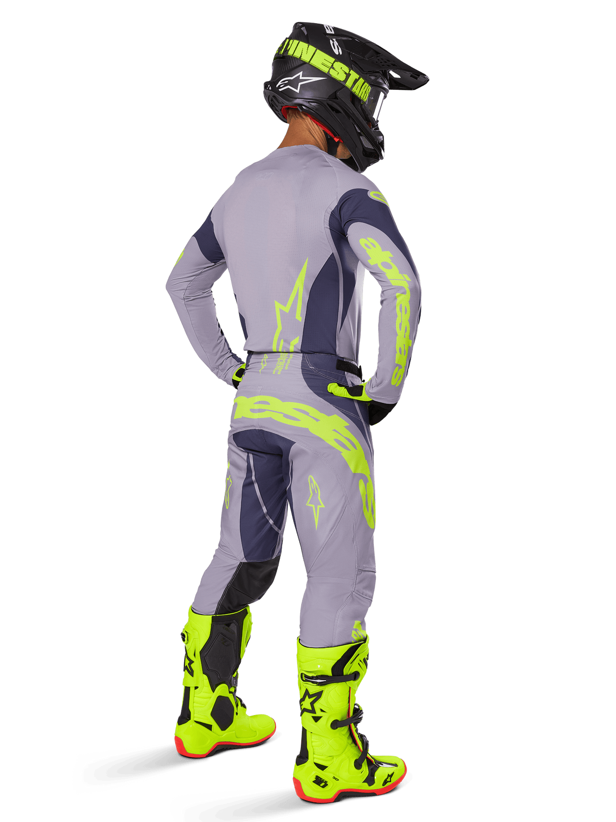 Motocrossförare sedd bakifrån iklädd Alpinestars 2025 Techstar Dreem Gear Set, grått och mörkgrått med fluorescerande gula logotyper, matchande tröja och byxor, svart hjälm med gula accenter och skarpt fluorescerande gula stövlar, koordinerad professionell racingoutfit för motocross.