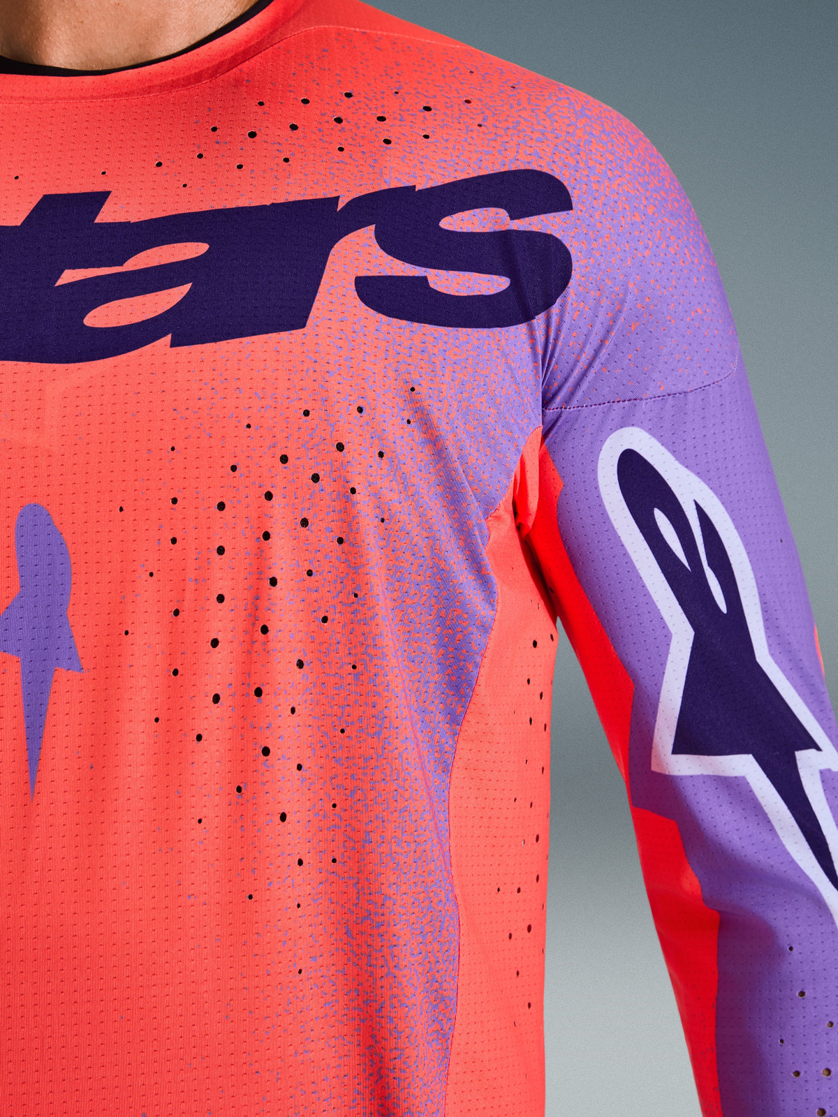 Alpinestars 2026 Supertech Scenz Jersey, motocrosströja, Hot Coral och lila, närbild som visar ventilerande mesh-textur och laserskurna perforeringar, stor lila bröstlogotyp och ärmgrafik för professionell terrängkörning