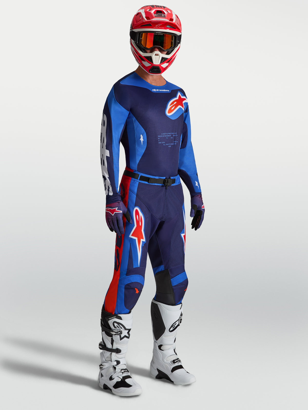 Alpinestars Racer Hunt tröja, högpresterande herr-motocrosströja i blått och rött, fukttransporterande polytyg med ergonomisk tävlingspassform, visas på modell med matchande byxor, vita stövlar och röd hjälm för terrängkörning