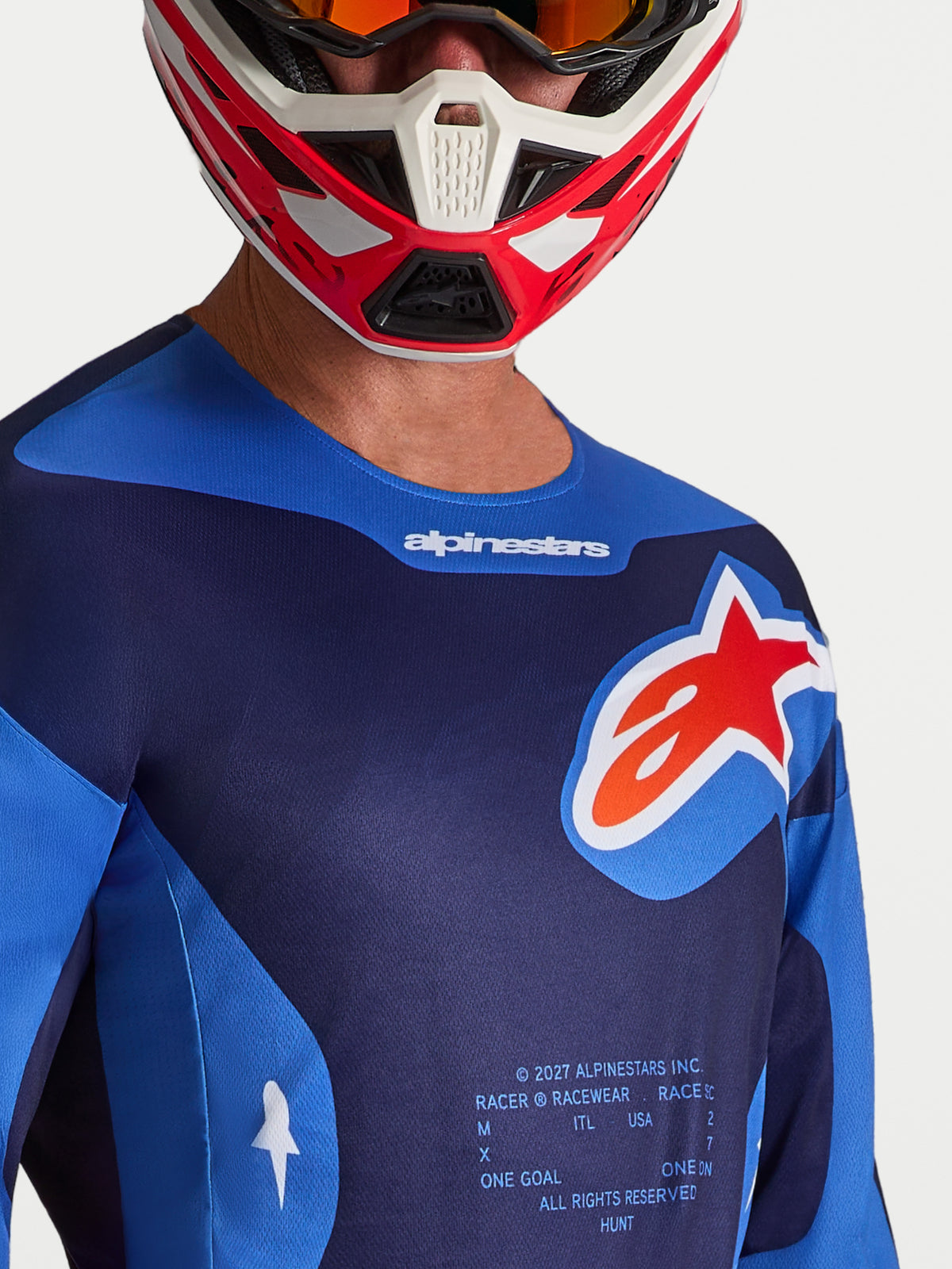 Alpinestars Racer Hunt tröja, motocrosströja för herr, blå och röd, närbild med fokus på bröstlogotyp och fukttransporterande polytyg, ergonomisk sportpassform för terrängkörning