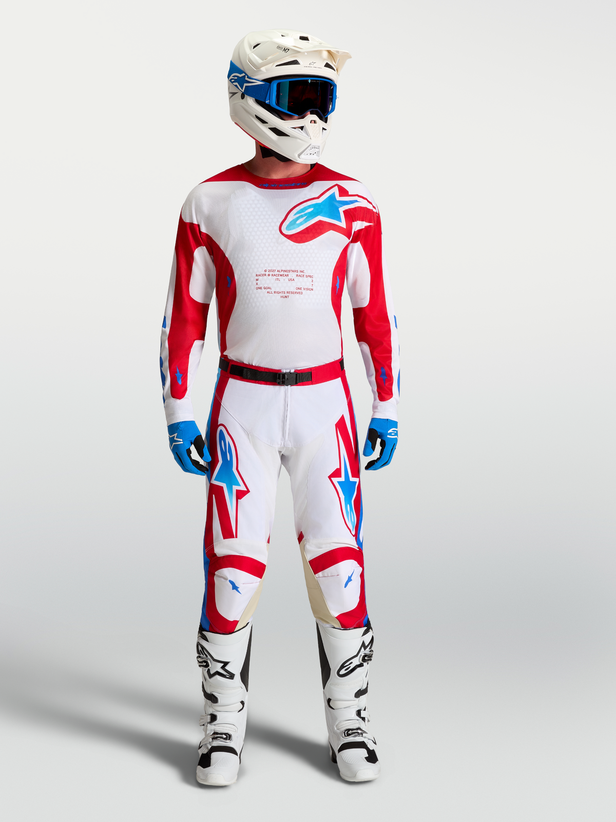 Alpinestars Racer Hunt motocrossutrustning, vit och röd med blå detaljer, förböjd ergonomisk passform, visas på modell.
