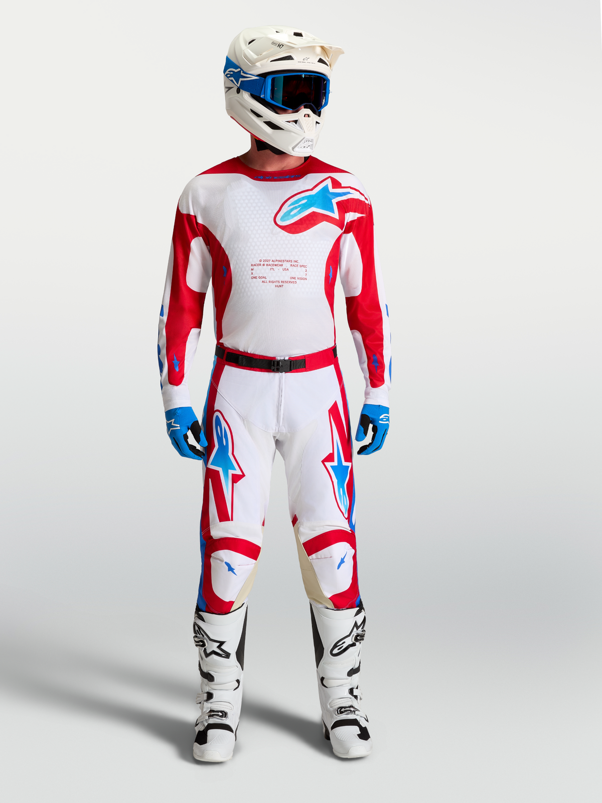 Alpinestars Racer Hunt tröja, vit och röd motocrossutrustning för herr med blå detaljer, matchande byxor och stövlar.