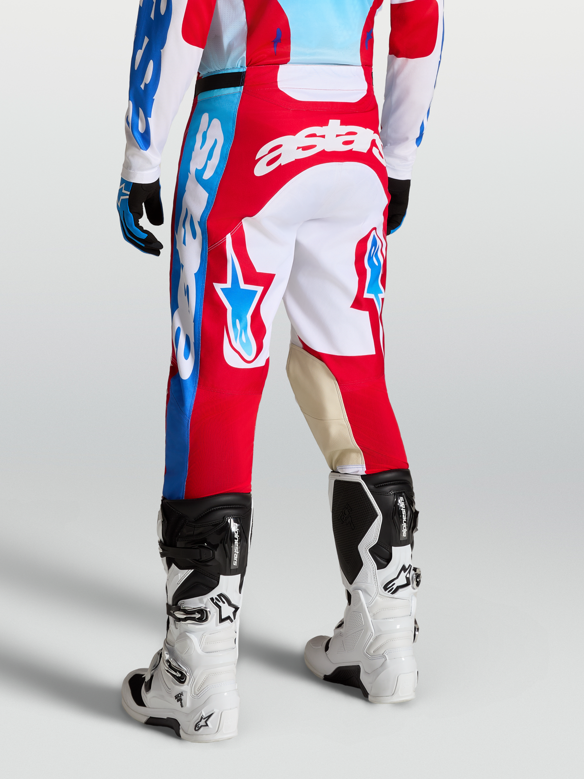 Alpinestars Racer Hunt byxor, röda och vita motocrossbyxor bärs av modell, med stjärngrafik och knäpaneler i getläder.