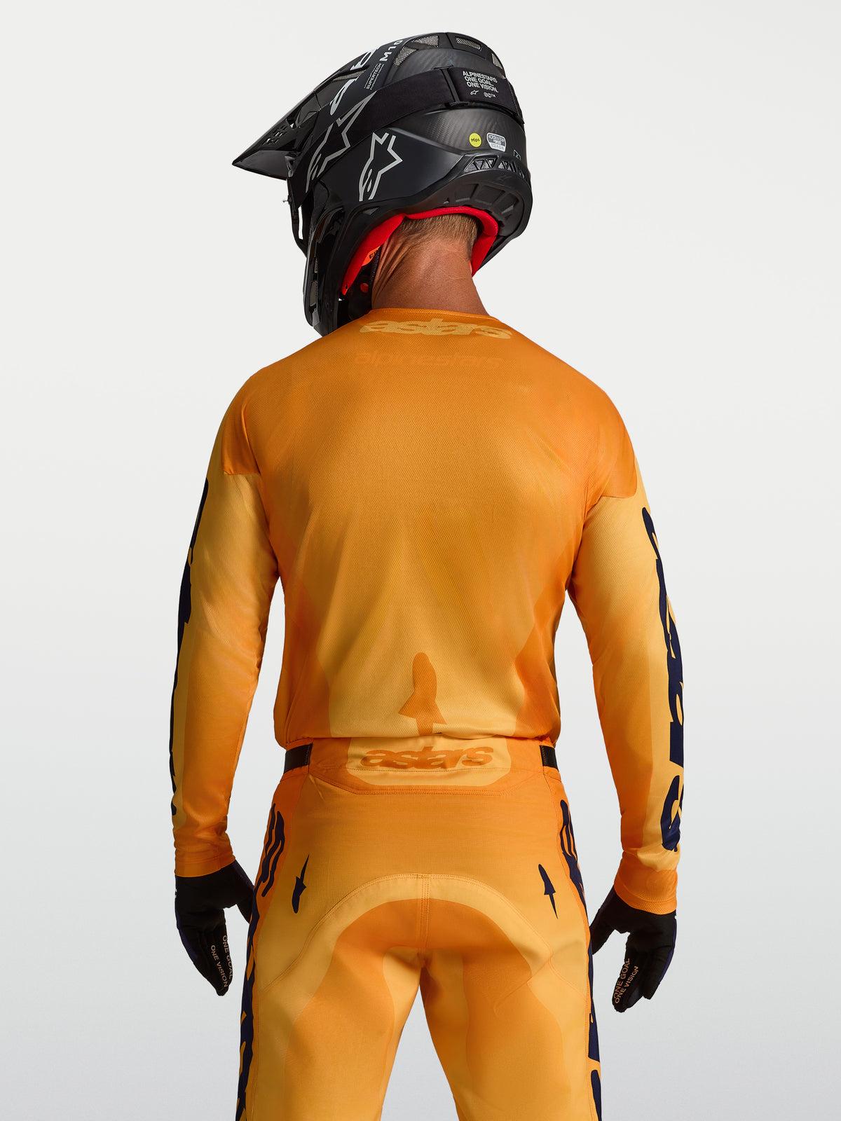 Alpinestars Racer Amber tröja, orange och guld motocrosströja för herr med ventilerande meshpaneler, sedd bakifrån på modell.