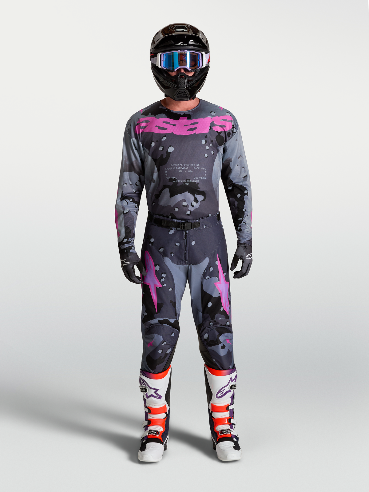 Alpinestars Racer Lone tröja och byxor i grå camo och lila, herrmodell med svart hjälm och vita motocrosstövlar.