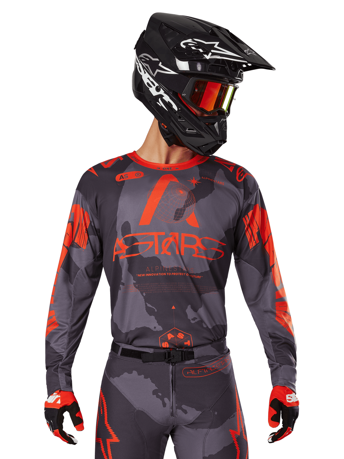 Alpinestars 2025 Racer Hollow-tröja, motocross-tröja, grått kamouflage och fluorescerande orange, bärs med matchande utrustningsset inklusive byxor och handskar, svart hjälm med vit grafik och goggles, tydlig ASTARS-logotyp, skyddande sportkläder för terrängkörning
