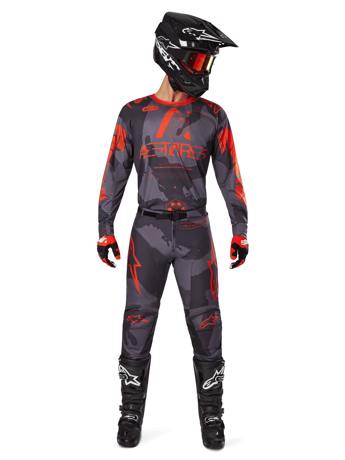 Alpinestars 2025 Racer Hollow Jersey och matchande byxor i Gray Camo Orange Fluo, komplett motocrossutrustning med svart hjälm, goggles, handskar och stövlar, framträdande orangea logotyper och kamouflagemönster.