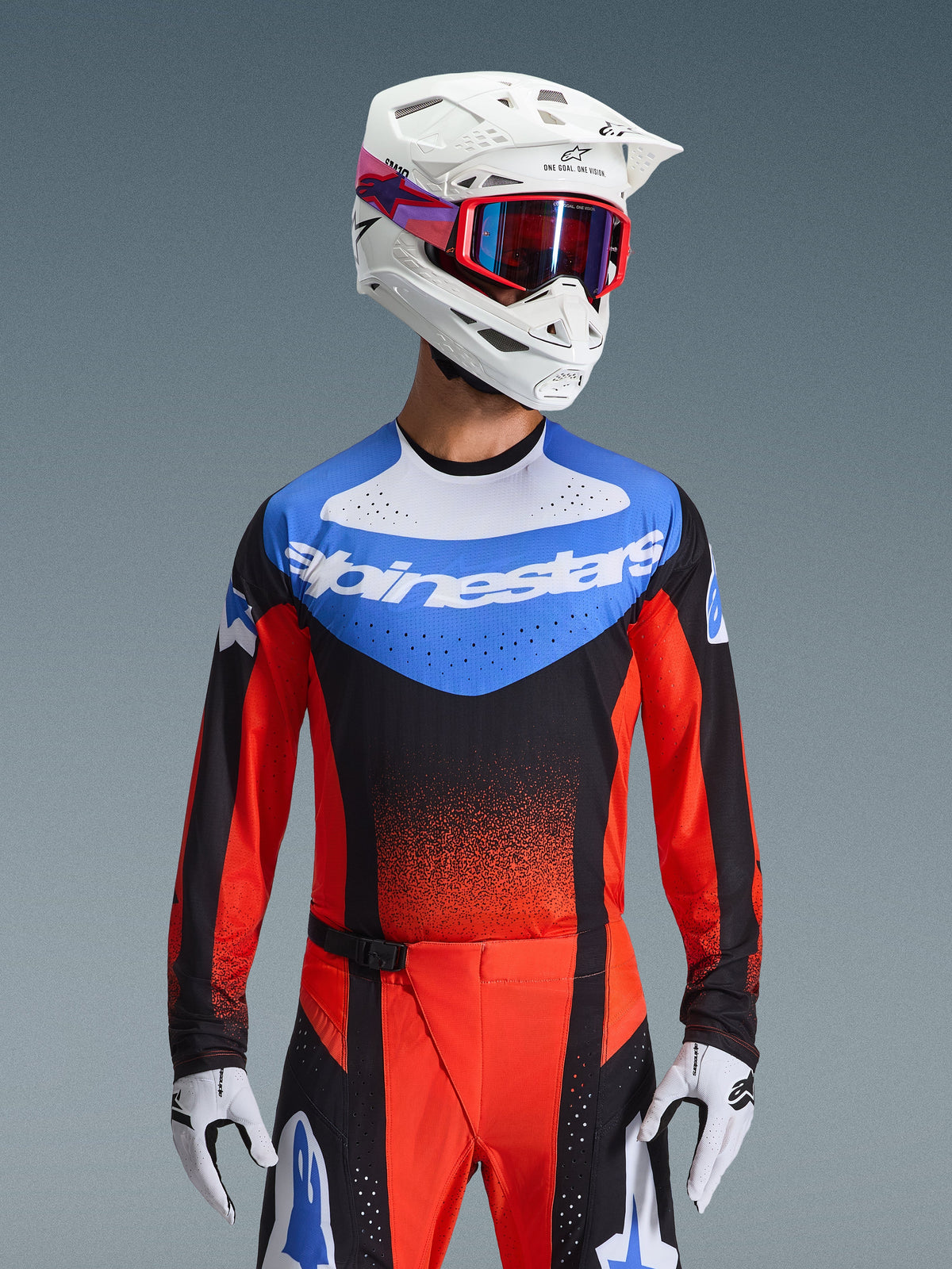 Alpinestars 2026 Techstar Knif Gear Set, Motocross racing gear featuring a blue, white, black and red jersey with Alpinestars branding, matching red and black pants, worn with a white helmet, red goggles, and white gloves, athletic performance fit for off-road competition