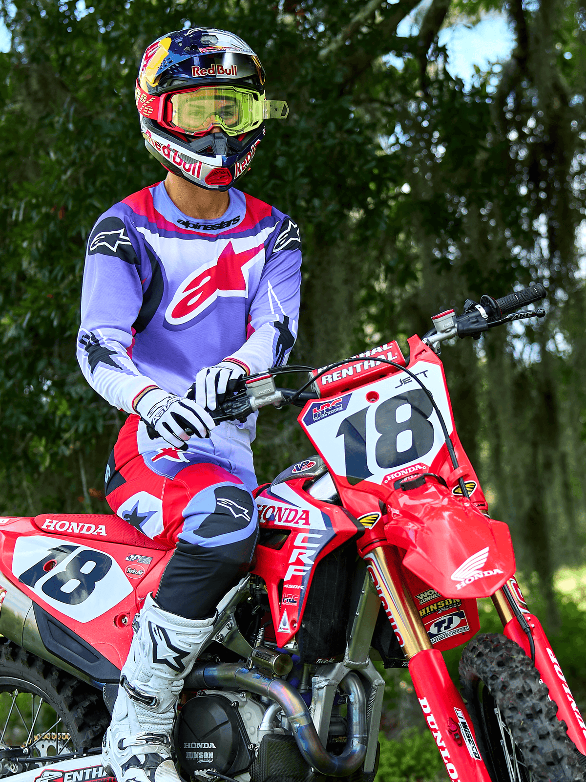 Motocross rider on a red Honda CRF dirt bike, wearing Alpinestars 2025 Fluid Wurx Jersey in Purple and Bright Red, matching purple and red pants, Red Bull helmet with yellow goggles, white Alpinestars boots and gloves, professional MX gear for off-road riding