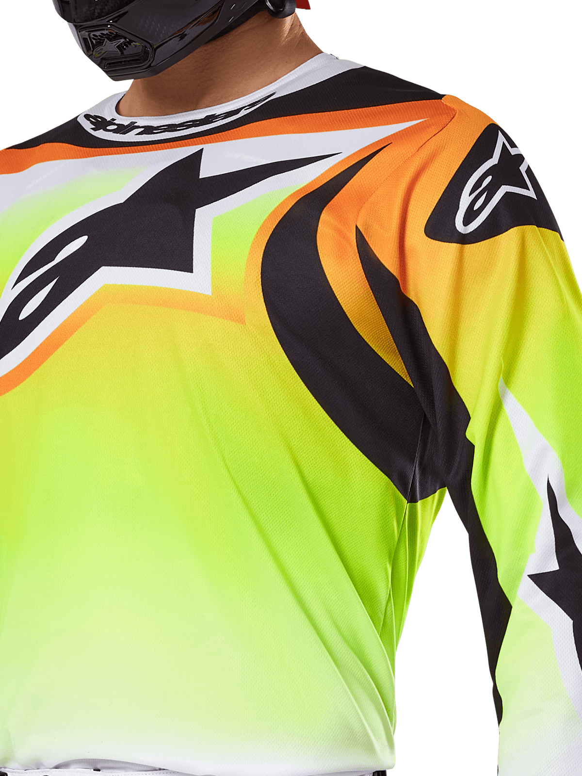Alpinestars 2025 Fluid Wurx-tröja, motocrosströja, fluorescerande gul med svart och orange grafik, med en stor svart Alpinestars-logotyp på bröstet och axeln, bärs av en förare med en svart hjälm.