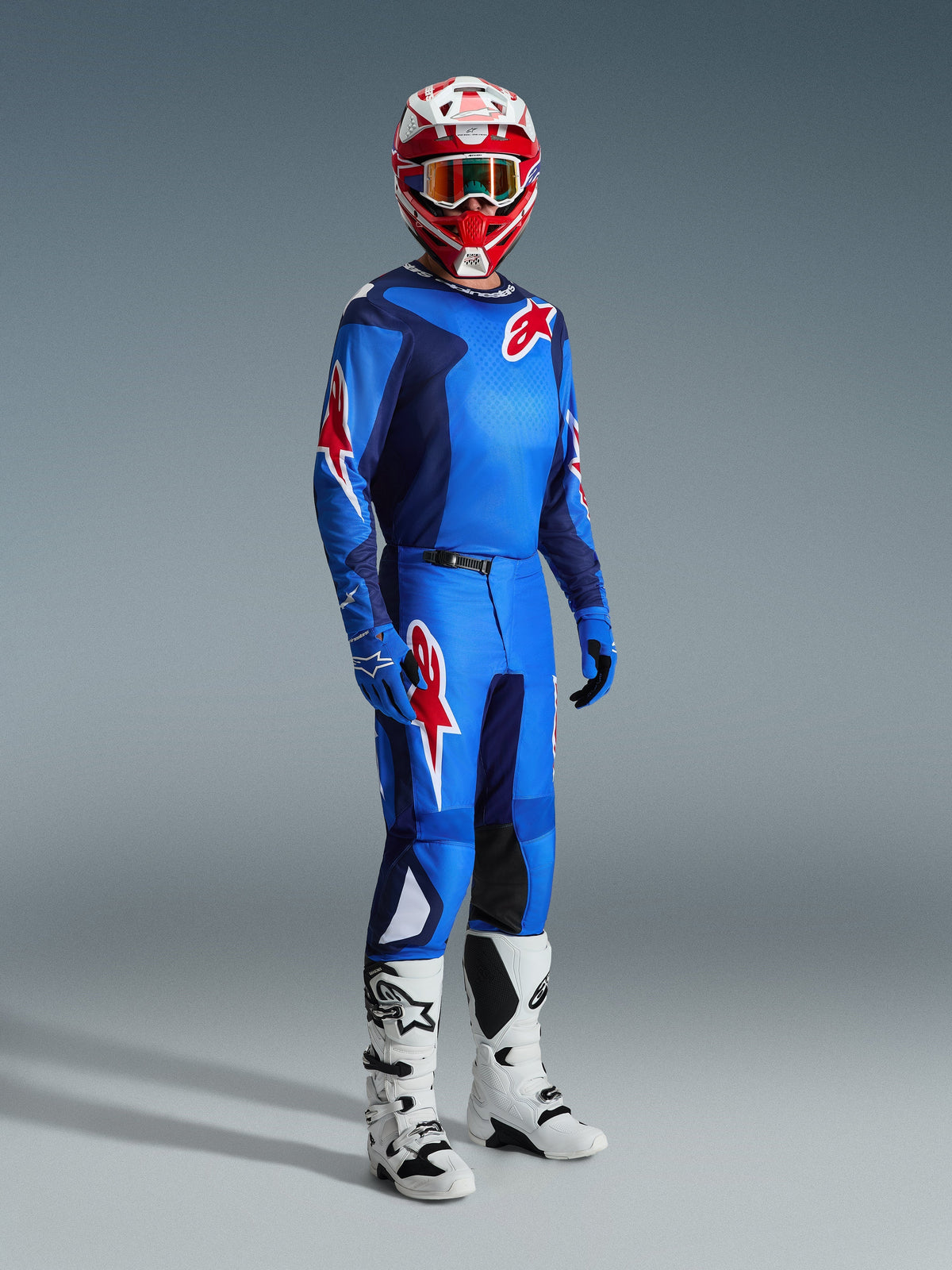 Motocrossförare bär Alpinestars 2026 Fluid Grid-tröja i Blue Red, matchande motocrossbyxor, vita och svarta stövlar och en röd och vit hjälm, professionellt utrustningsset för offroad-prestanda.
