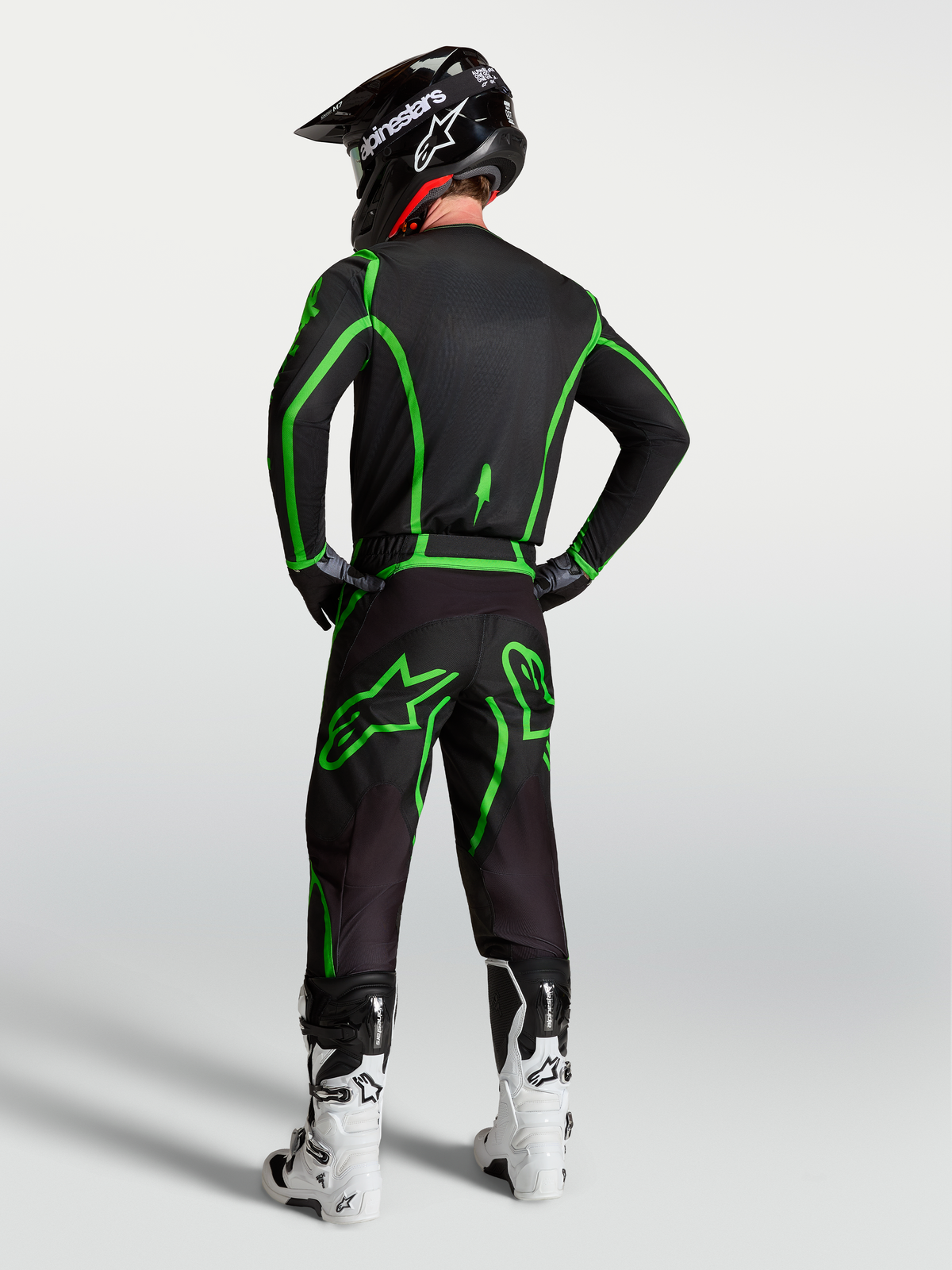 Alpinestars Fluid Apex V2 tröja, svart och neongrön motocrosströja, vy bakifrån på modell med matchande byxor och hjälm.