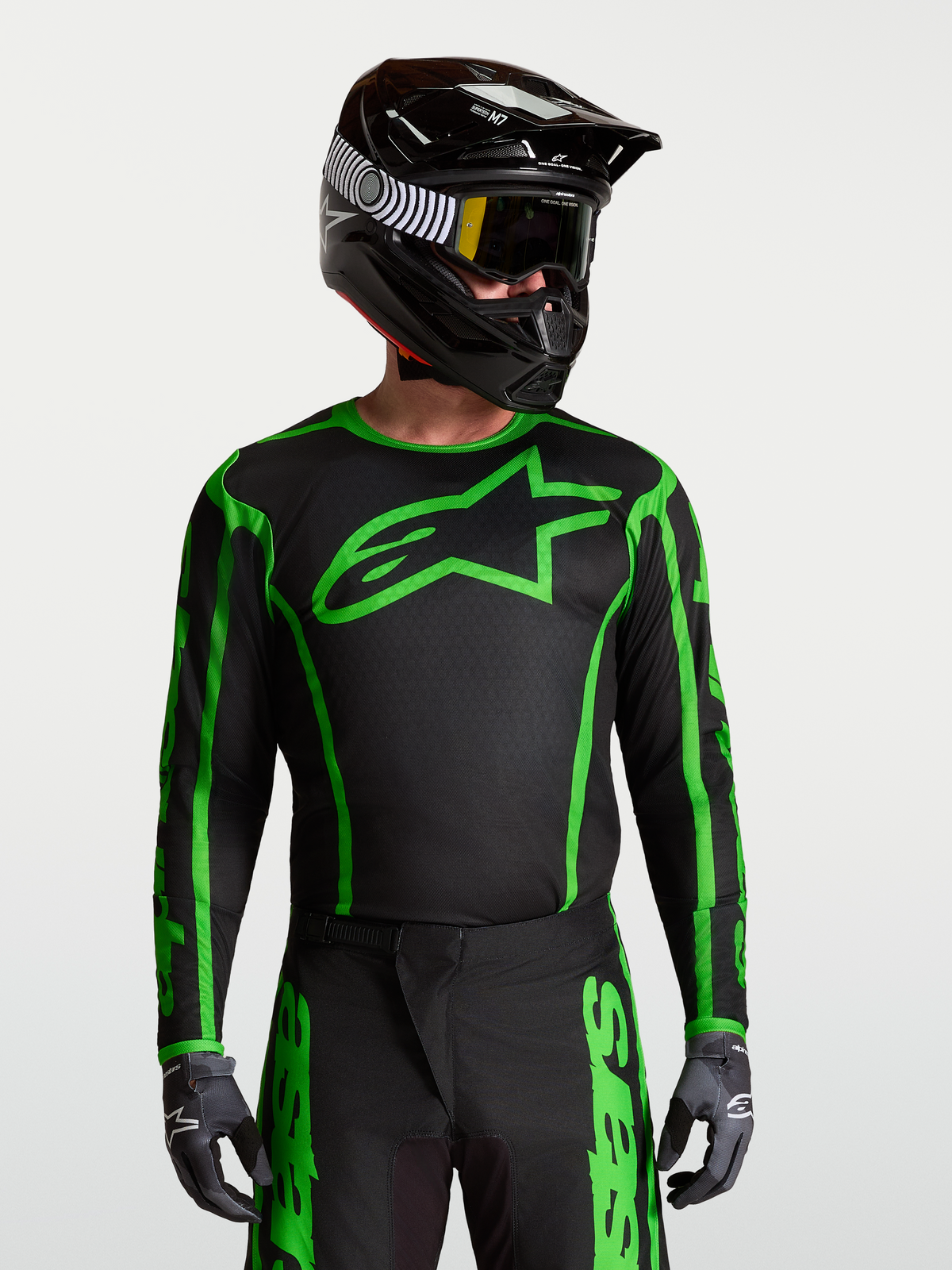 Alpinestars Fluid Apex V2 tröja, motocrosströja i svart och grönt fluo på modell med hjälm, fukttransporterande material för terrängkörning.